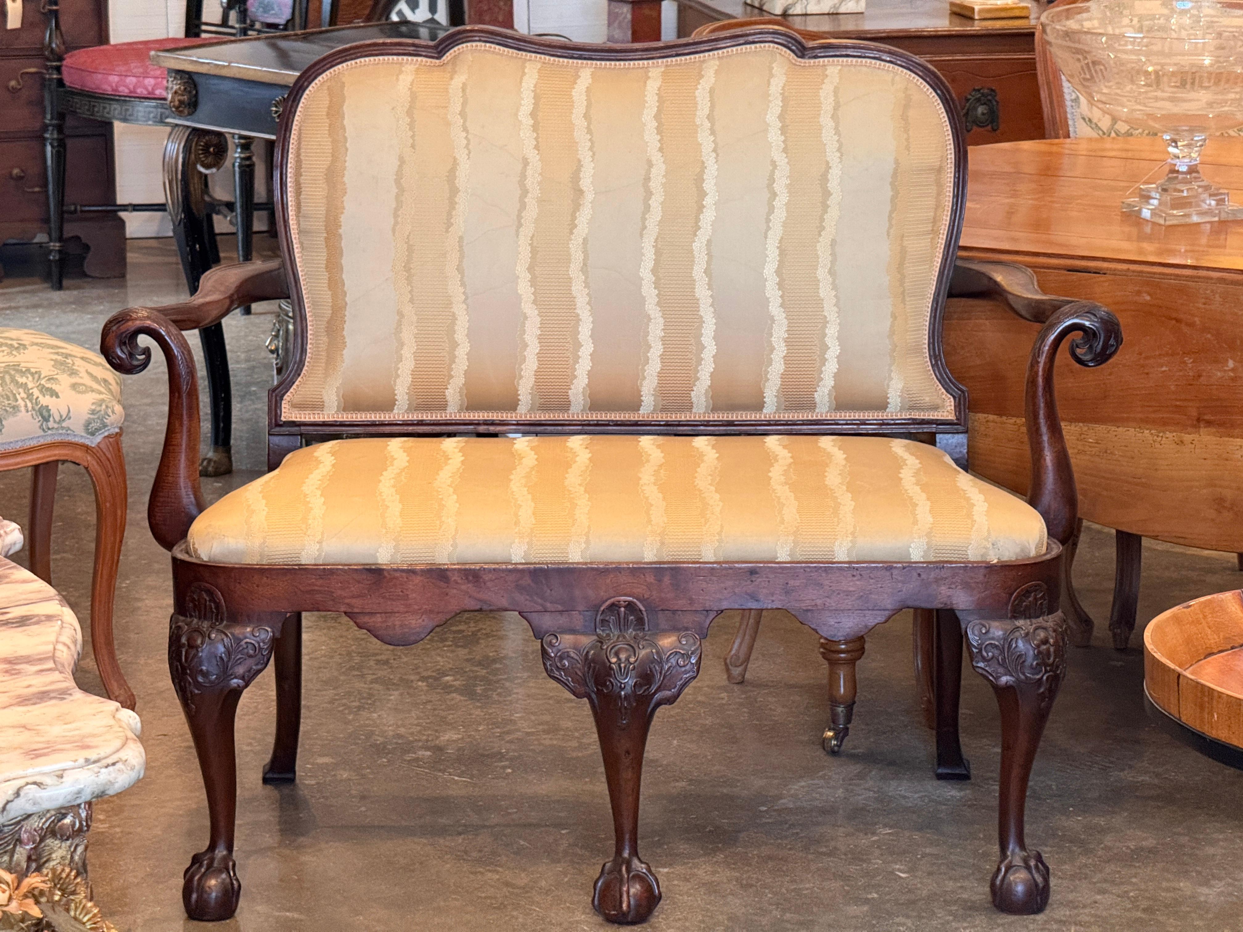 Divano inglese del XIX secolo con influenze irlandesi, caratterizzato da braccioli, ginocchia intagliate ad acanto e piedi a sfera. Lo schienale e la seduta imbottiti e sagomati sono sostenuti da una struttura in mogano riccamente intagliata, che