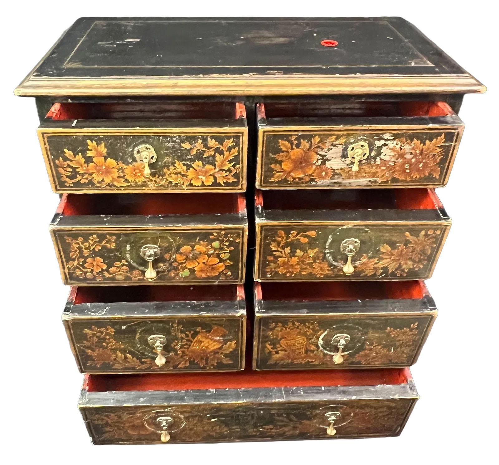 Un armadietto per le spezie a sette cassetti di dimensioni ridotte dell'inizio del XIX secolo, splendidamente rifinito con urne dipinte a mano e delicati motivi floreali, che presenta una patina fine e sottili segni dell'età. Ogni stretto cassetto è