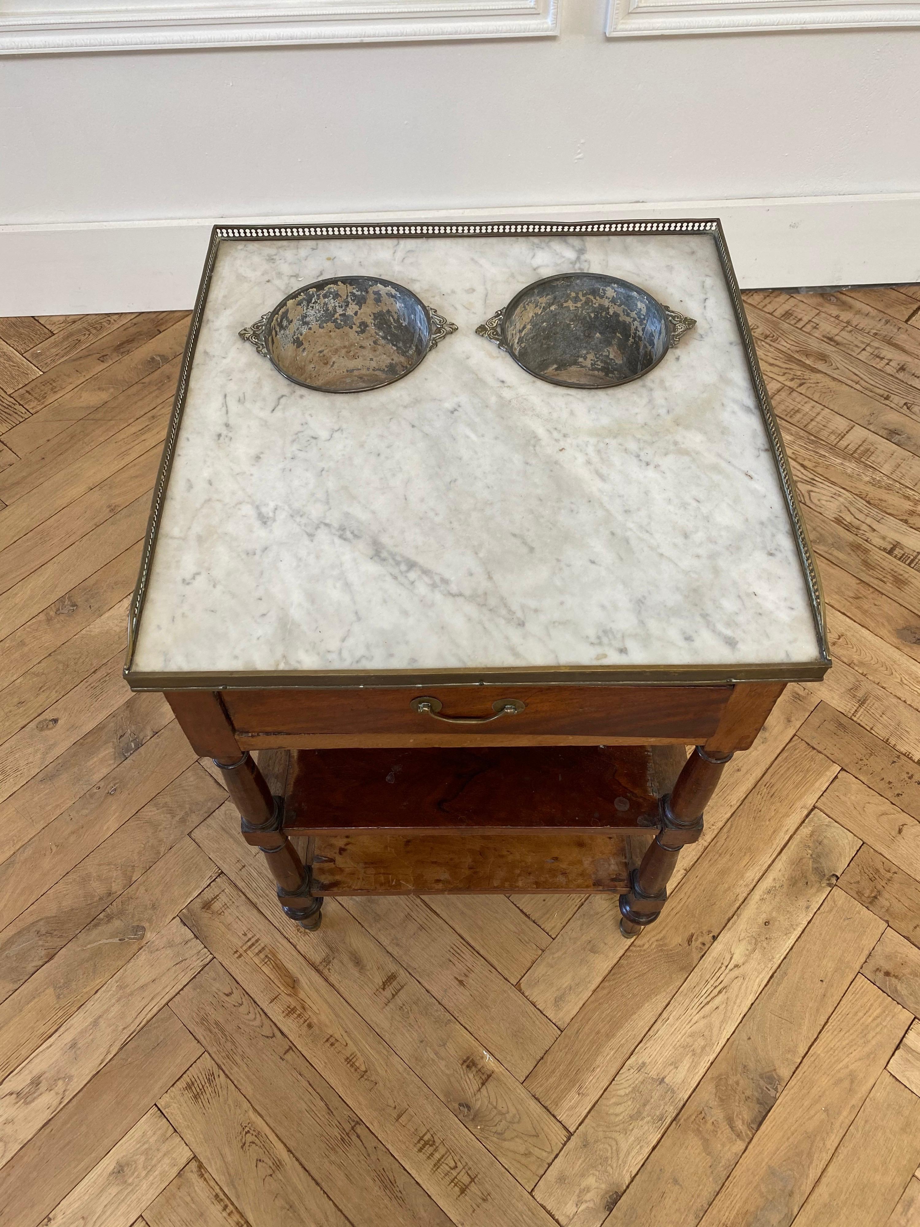 19th century English shaving table with marble top and metal tin buckets.
Great as a side table, or even to hold greenery.
Solid and sturdy, has 1 drawer, with shelves.
  