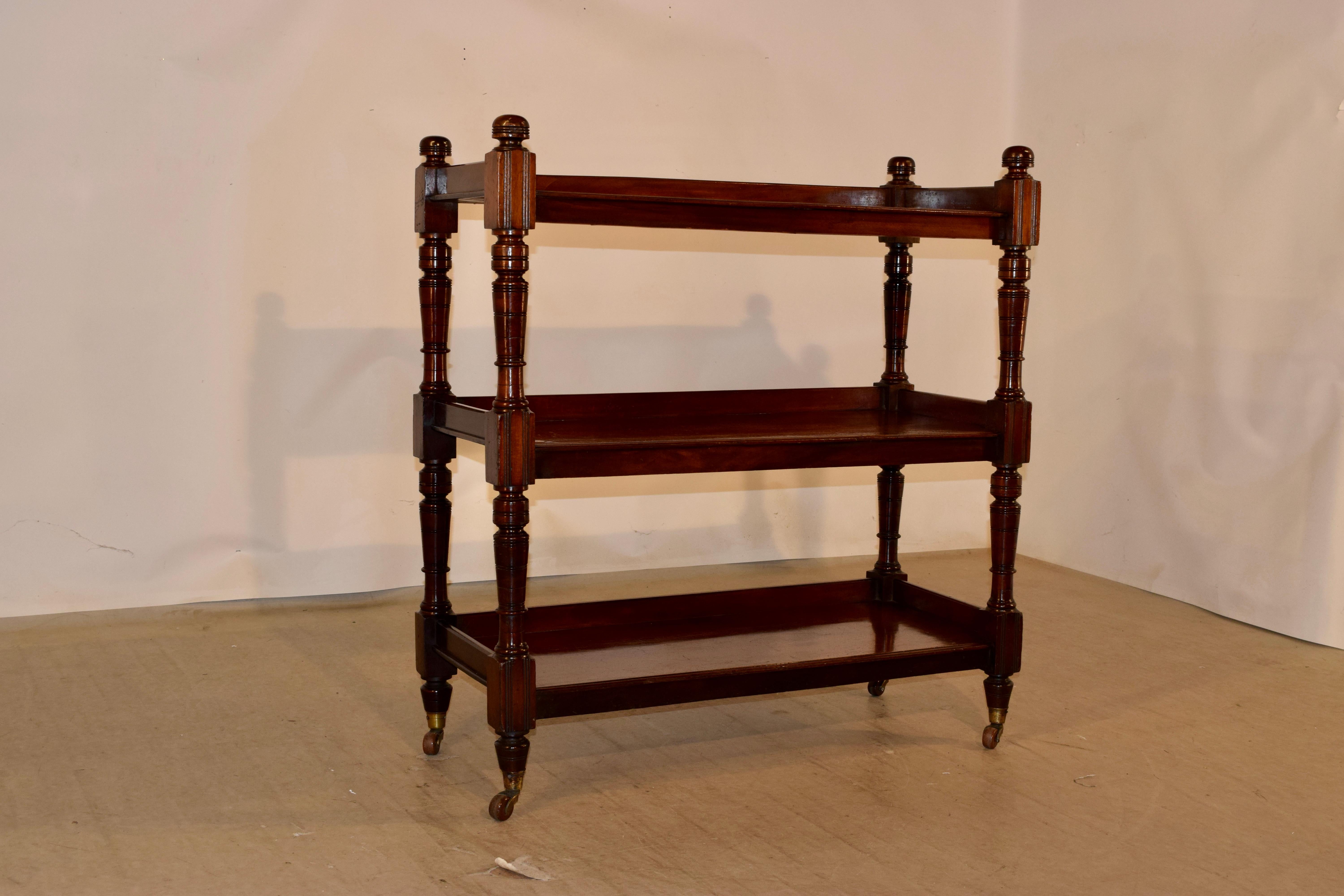 19th century mahogany shelf from England with hand turned finials over three shelves, all with galleries on three sides and beveled edges on the fronts. The legs which join the shelves are hand turned and the piece is supported on what appear to be