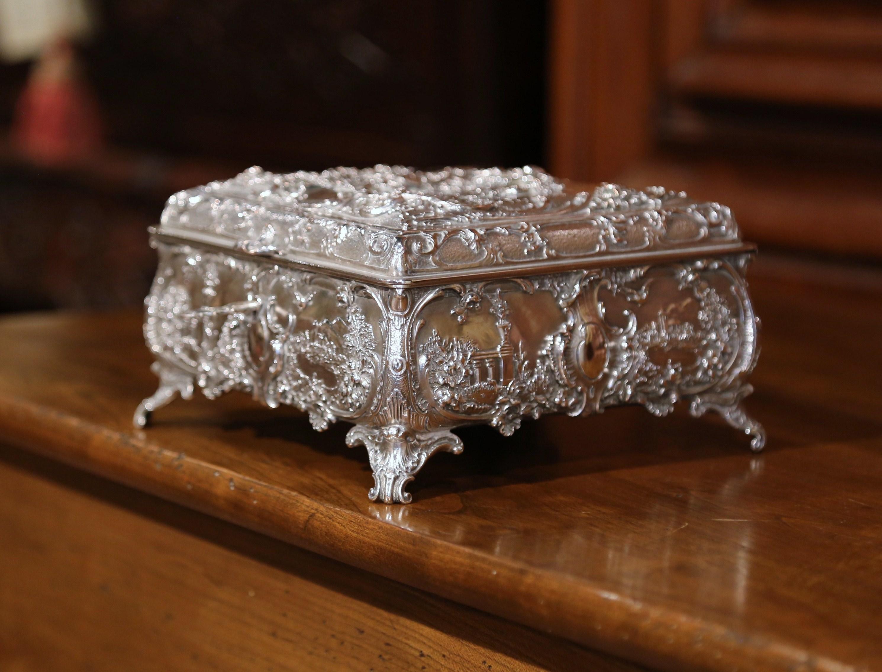 Place this elegant antique silver coated copper box in your master bath to keep your jewelry safe and organized. Crafted in England circa 1880, the ornate square casket sits on intricate scroll feet; the box features four bow sides decorated with