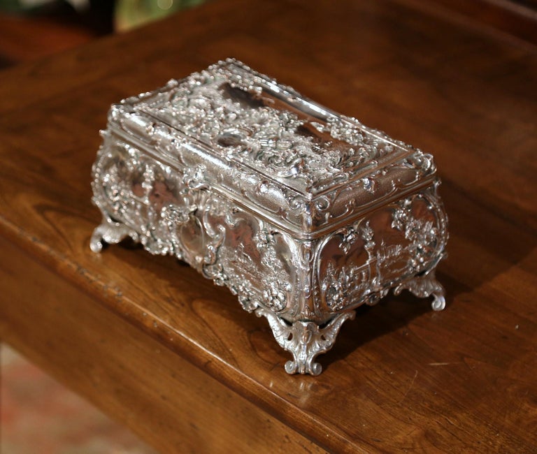 Place this elegant antique silver plated on copper box in your master bath to keep your jewelry safe and organized. Crafted in England, circa 1880, the ornate rectangular casket sits on four scroll feet and has four bow sides embossed with foliage,
