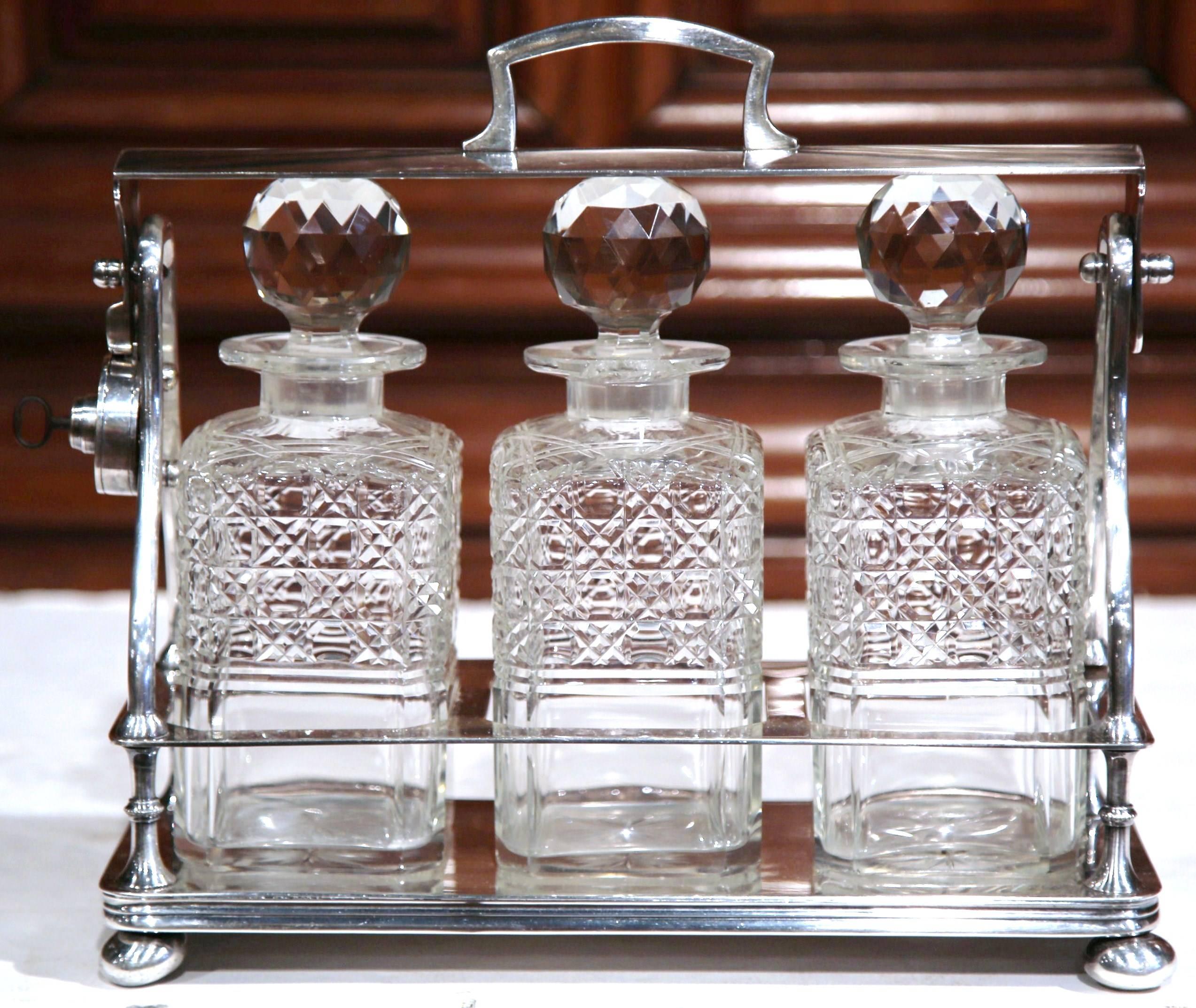 Entertain in style with this beautifully crafted, antique Tantalus from England. Crafted, circa 1860, the bar accessory features three cut-glass carafes with decorative round stoppers. The top handle can be locked for protective purposes and to keep