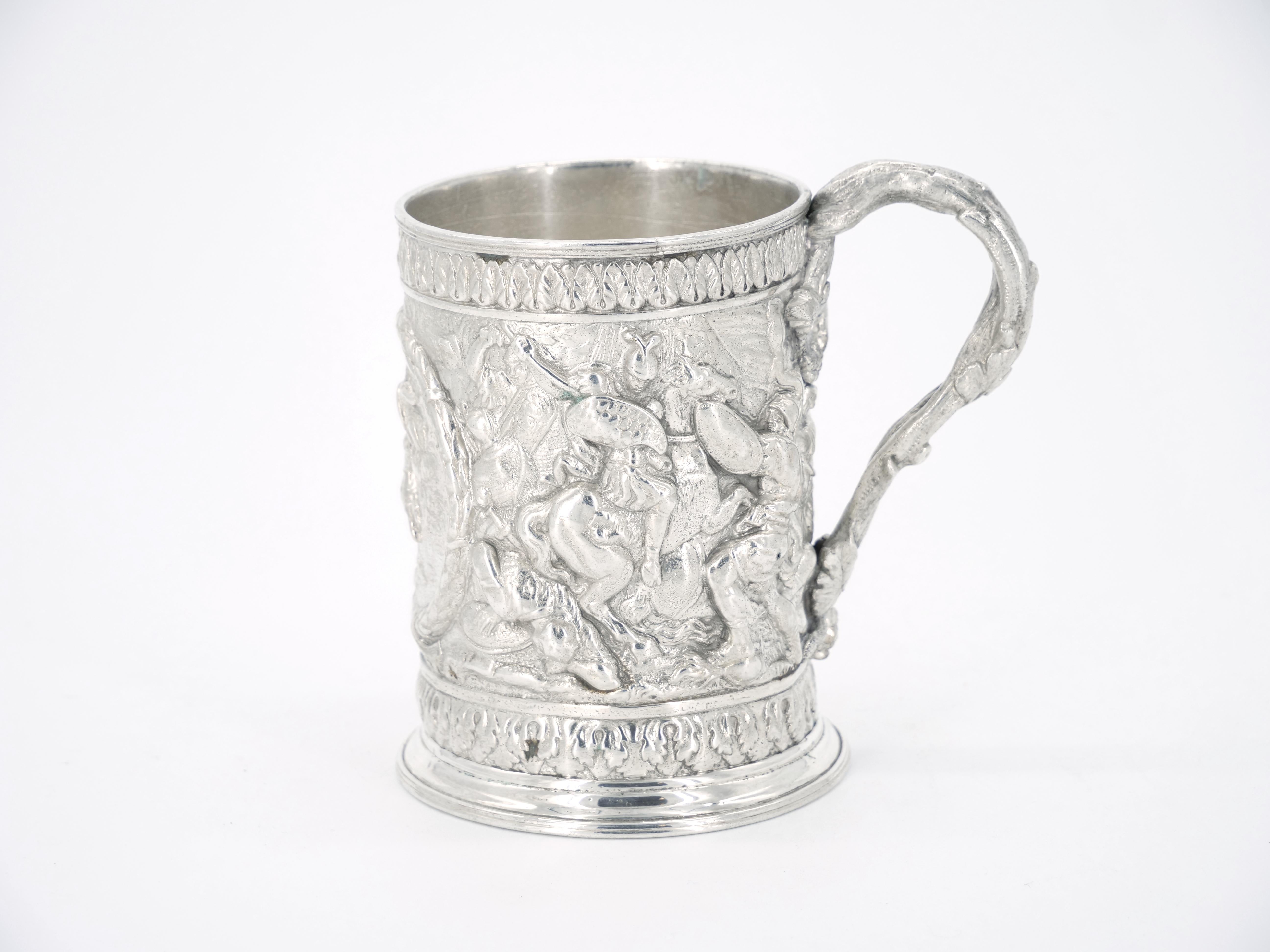 Mug en métal argenté anglais de la période victorienne du dix-neuvième siècle avec d'exceptionnels motifs repoussés en haut relief, dont une couronne centrale représentant des chevaliers à cheval en train de combattre avec deux scènes