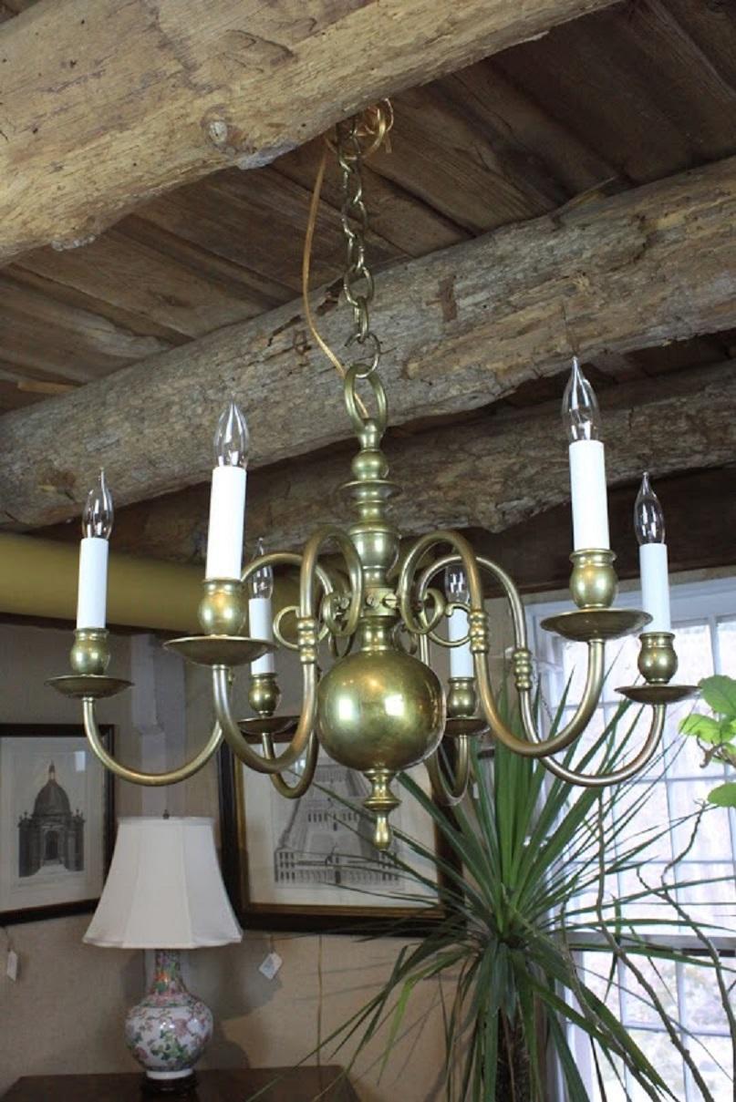 Late 19th century English brass chandelier with six scrolled arms attached to a turned column ending with brass orb and finial.