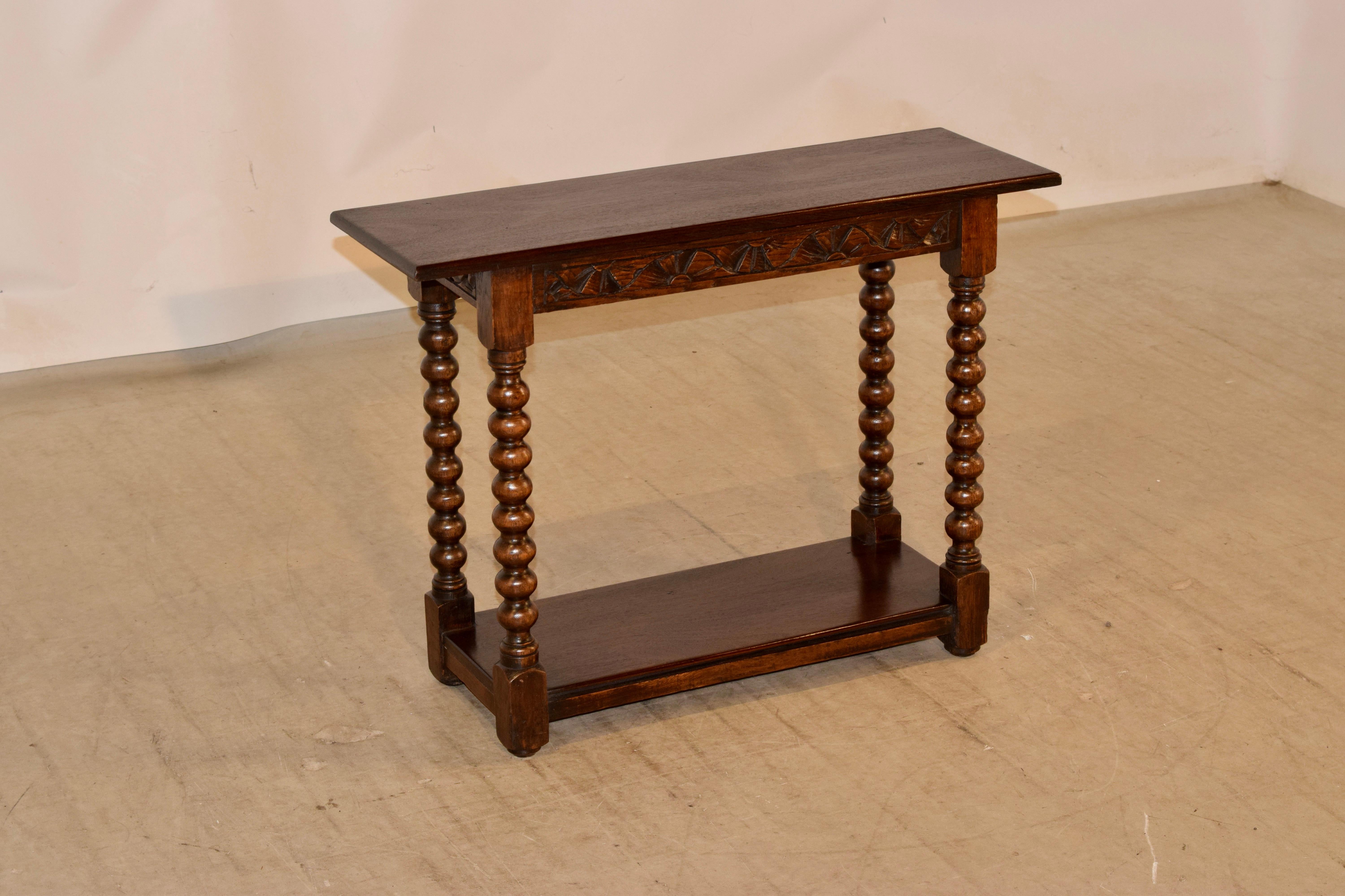 19th century slender bench from England made from oak and mahogany. The top and lower shelves are made from single mahogany planks and are a wonderfully grained contrast to the oak frame. The mahogany top follows down to a hand carved decorated