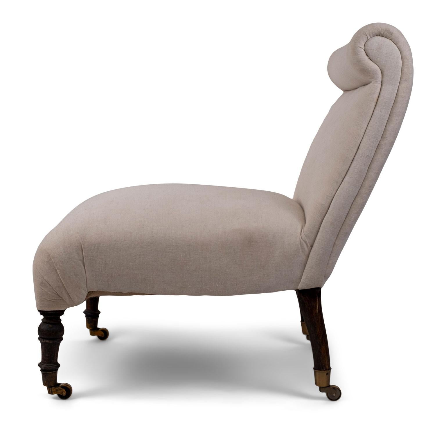 19th century English slipper chair on casters: roll-shape back, turned front legs and remnants of brown paint on legs. Covered in vintage muslin (to be upholstered in your own fabric).