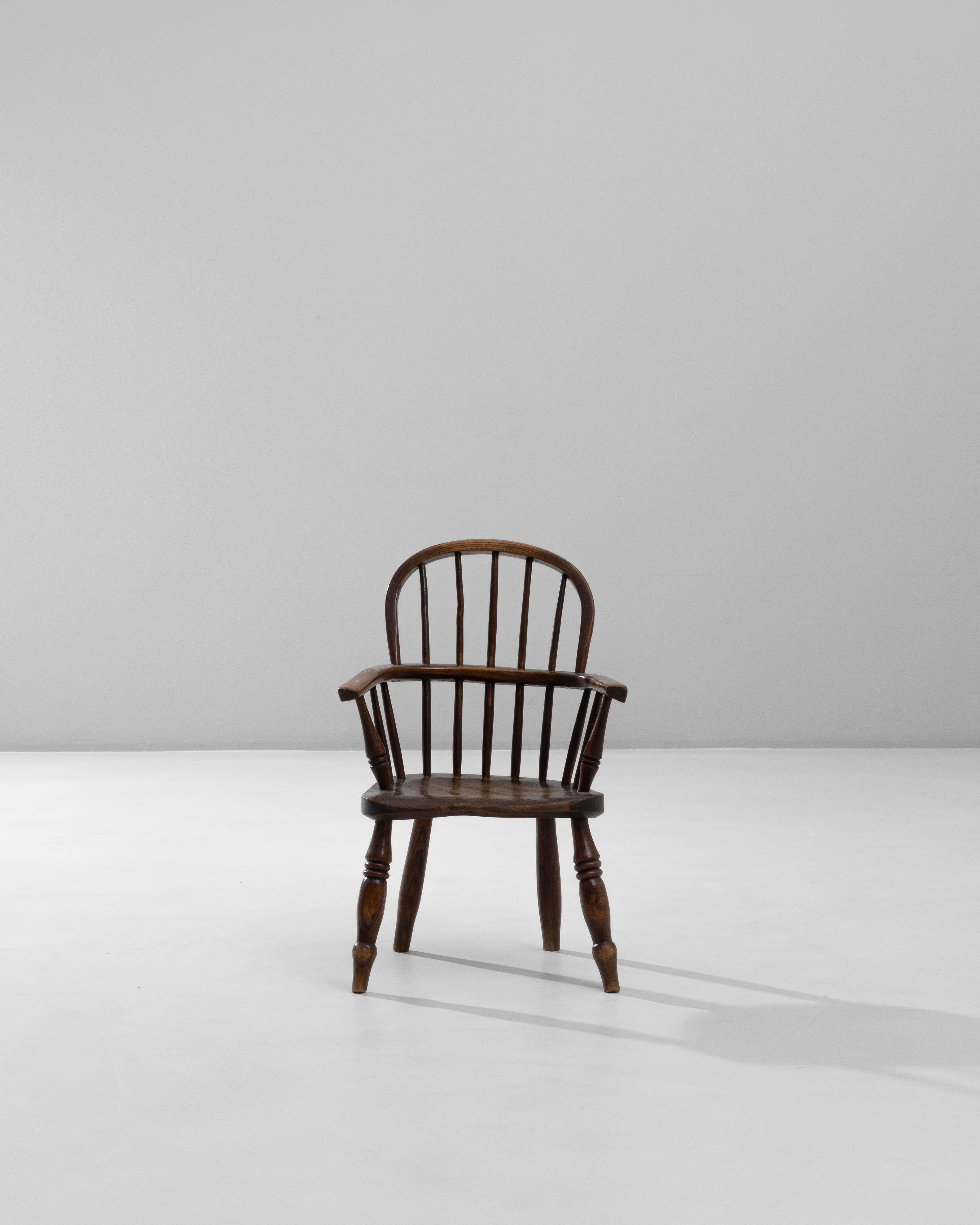 19th Century English Small Spindle-Back Wooden Armchair. This charming, petite armchair reflects the classic craftsmanship of 19th-century English country furniture. Made from solid wood with a warm, aged patina, it features a curved crest rail and