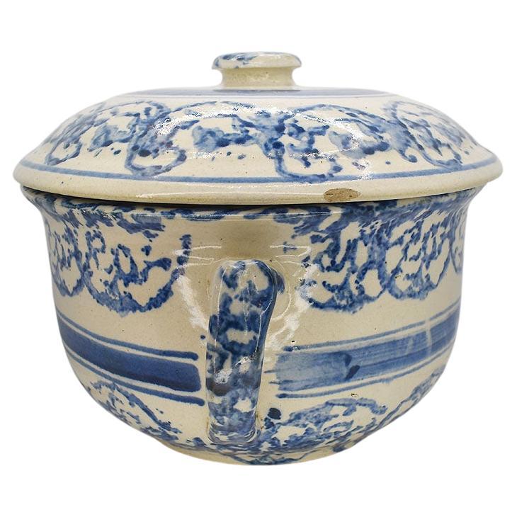A fabulous antique ceramic crock in blue and cream with a lid. This rare serving dish features a wide-body and the original lid. The side of the piece has an applied handle and a lid with a round button knob. It is decorated with blue sponge paint