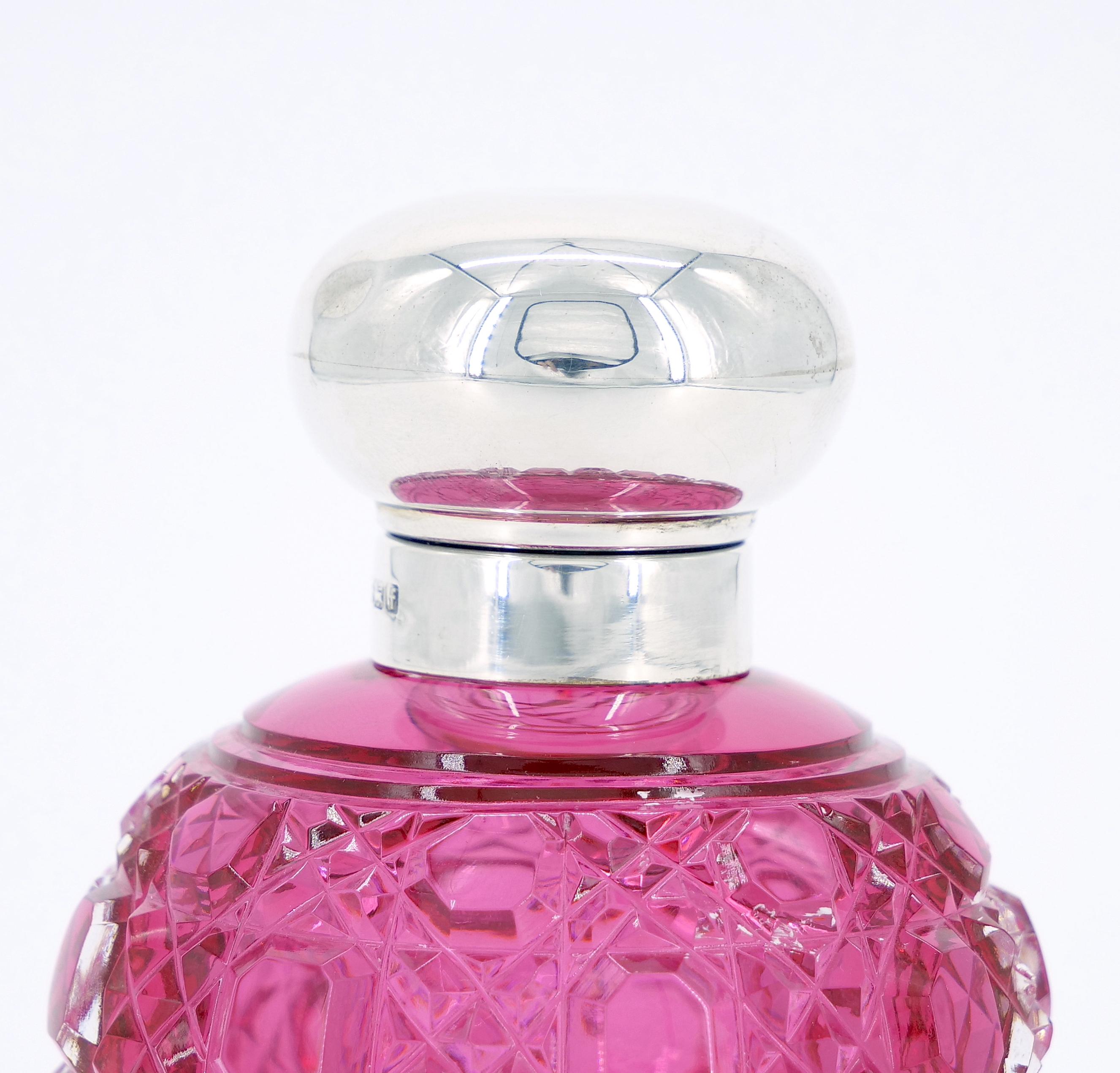 Transport yourself to the elegance of the 19th Century with this exquisite English Sterling Silver Covered Top and Cranberry brilliant Cut Glass Perfume Bottle. The perfume bottle showcases a hobnail sterling silver top complemented by an engraved