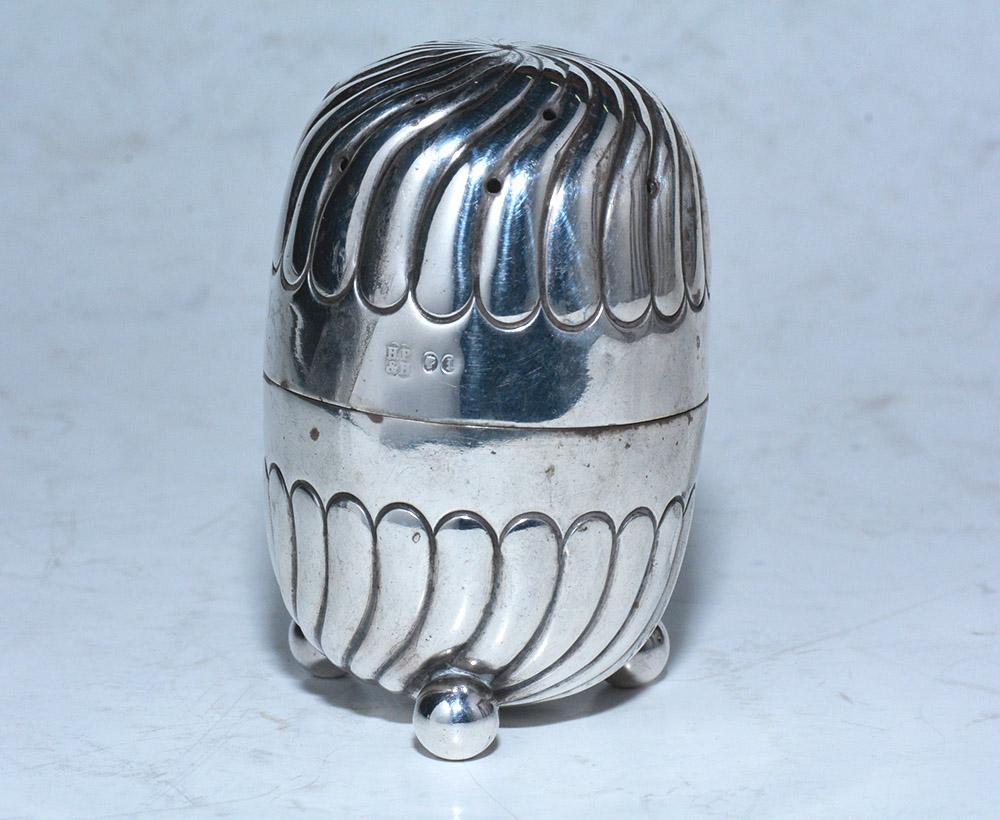 The 19th century sterling silver salt shaker stands on three ball feet and separates at the waist level. The bottom is stamped 