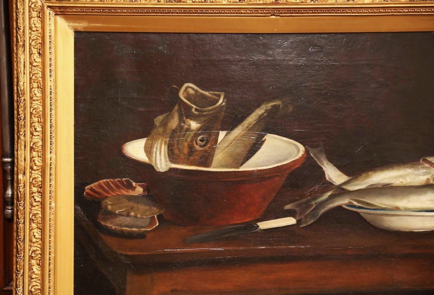 This antique, kitchen still life painting was painted in England in the 19th century. Signed on the bottom left corner and dated 1847, the canvas is set in its original carved gilt wood frame. The composition features two pots with fish that are