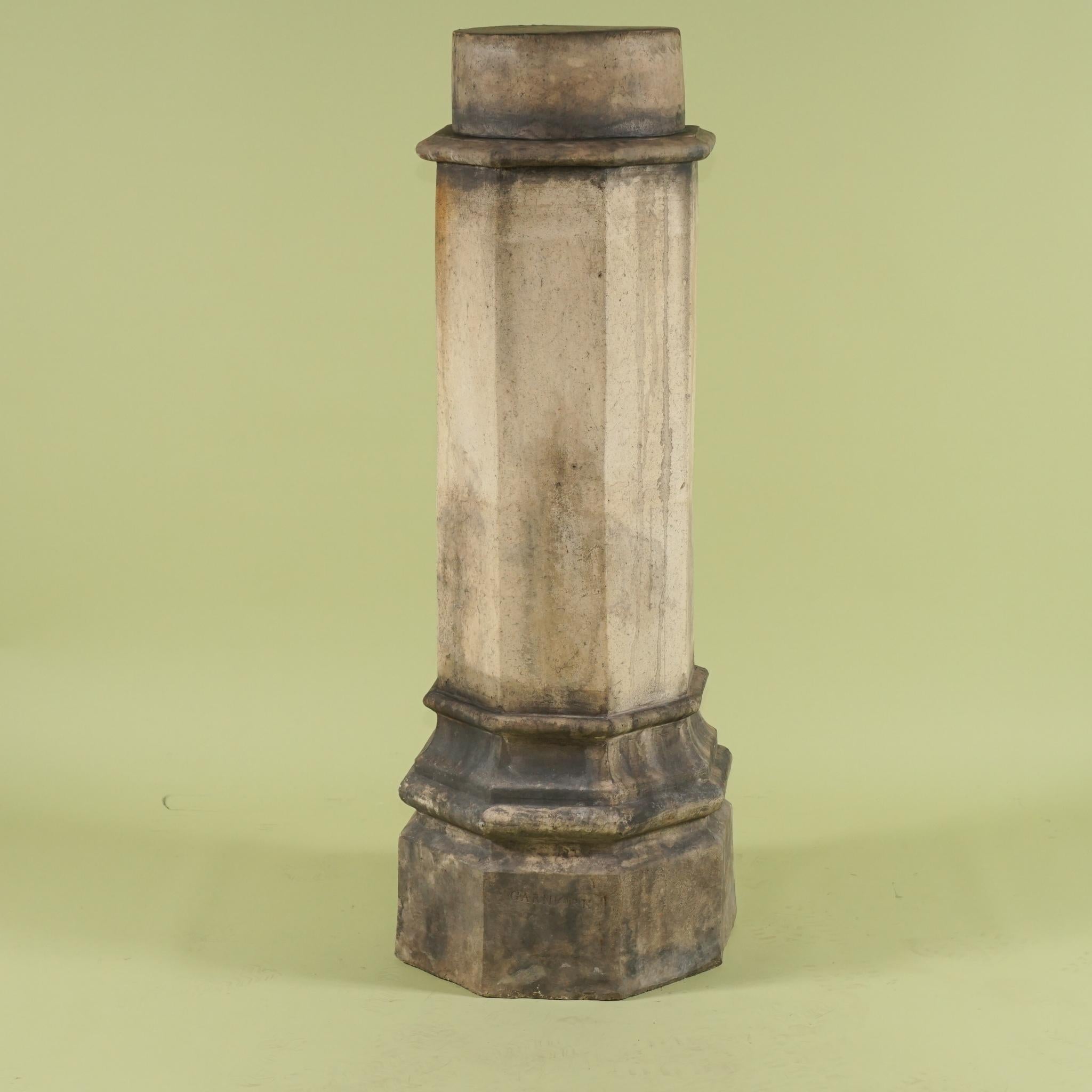 This tall and dramatic pedestal created of English terracotta was made in the mid 19th century. Fashioned in a modeling process the piece is stamped by the maker and has an amazing and wonderful old patina from many many years of outdoor use. The