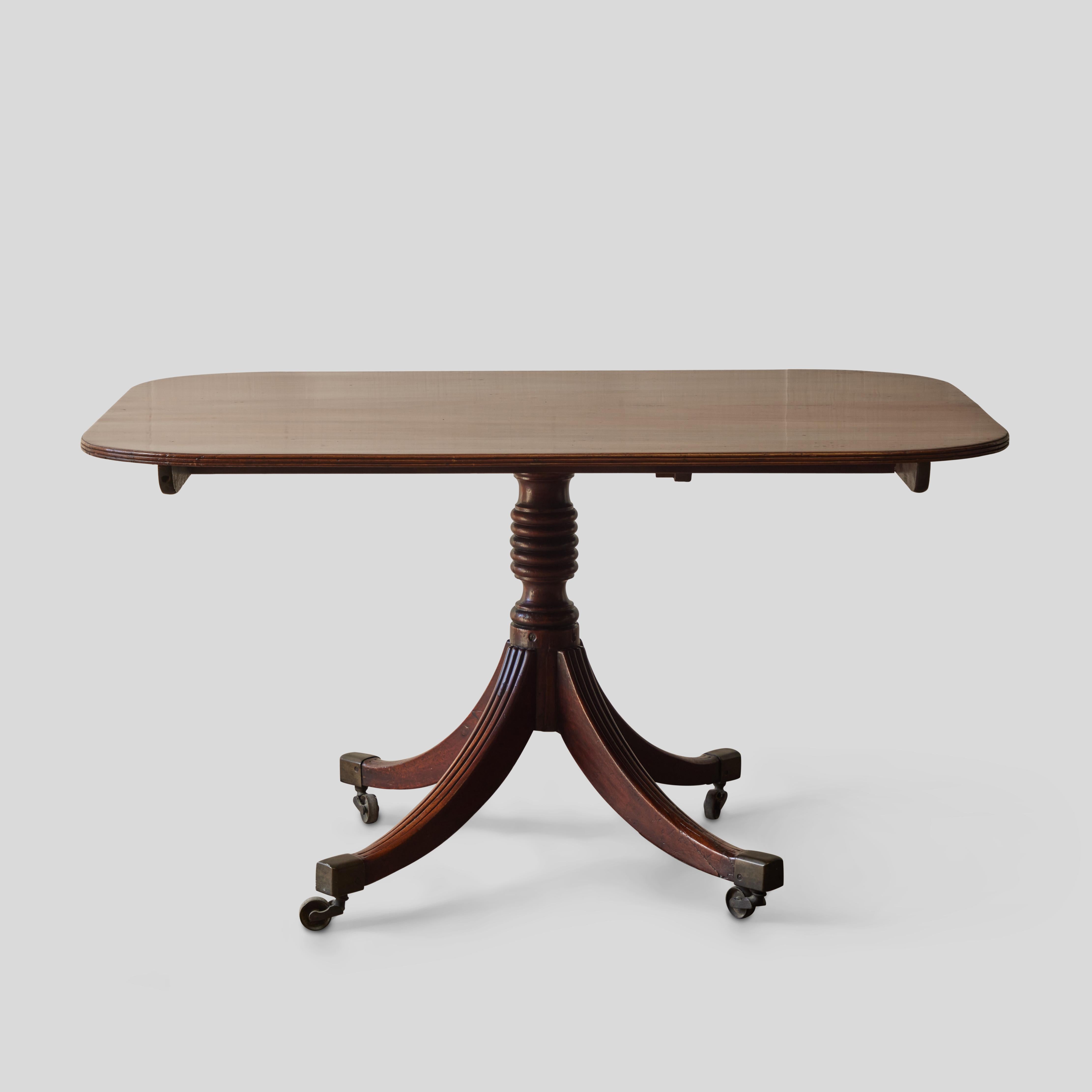 Late Victorian mahogany breakfast or side table with rounded rectangular top, gathered pedestal base and four saber-style legs set on casters.

England, circa 1860

Dimensions: 53W x 38D x 30H