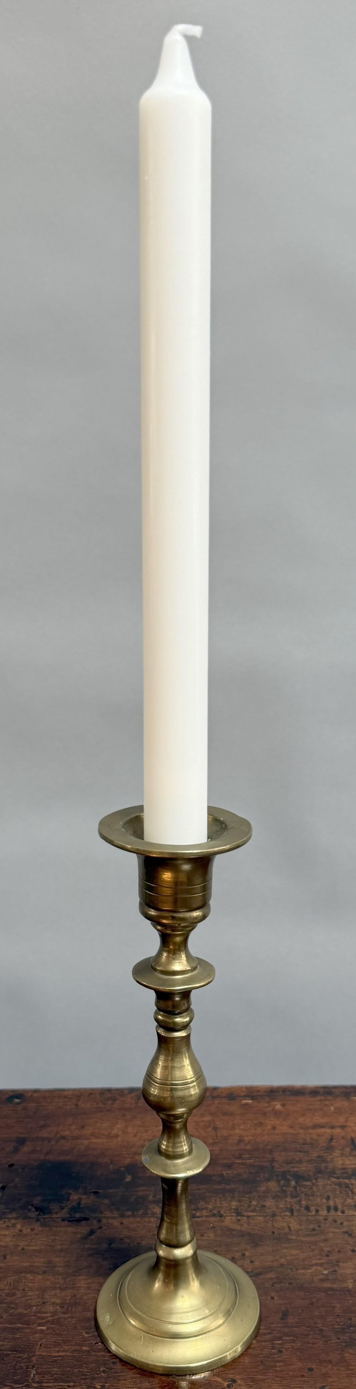 An exquisite example of early Victorian metalwork! This single brass candlestick was crafted in England circa 1840. Elegantly proportioned, the piece features a finely turned baluster stem rising from a broad circular foot, culminating in a wide