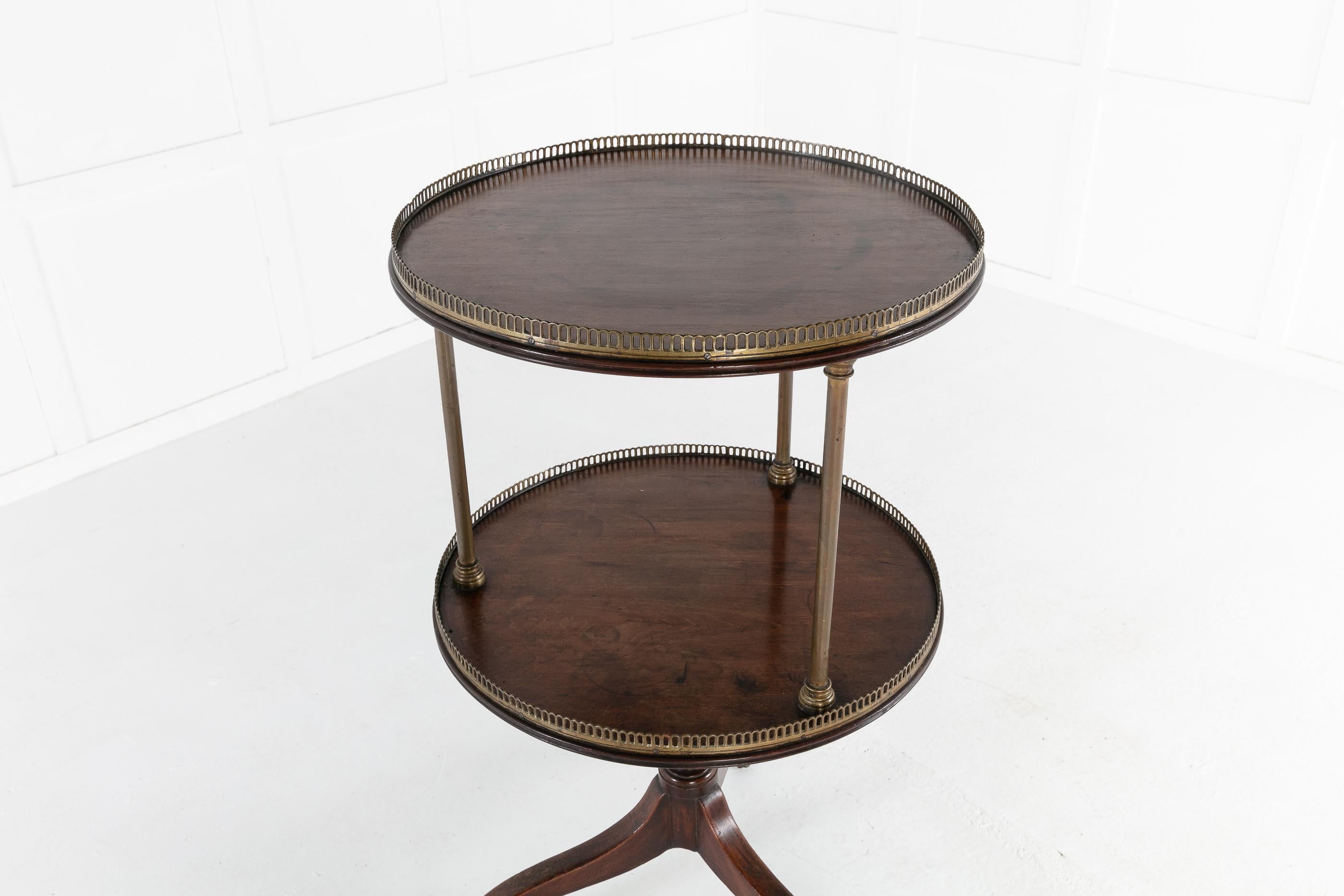 19th century English Regency mahogany two-tier dumb waiter. Each circular tier surmounted with original pierced brass gallery and supports. Raised on a tripod base ending in brass sabot and casters. Having nice proportions.
