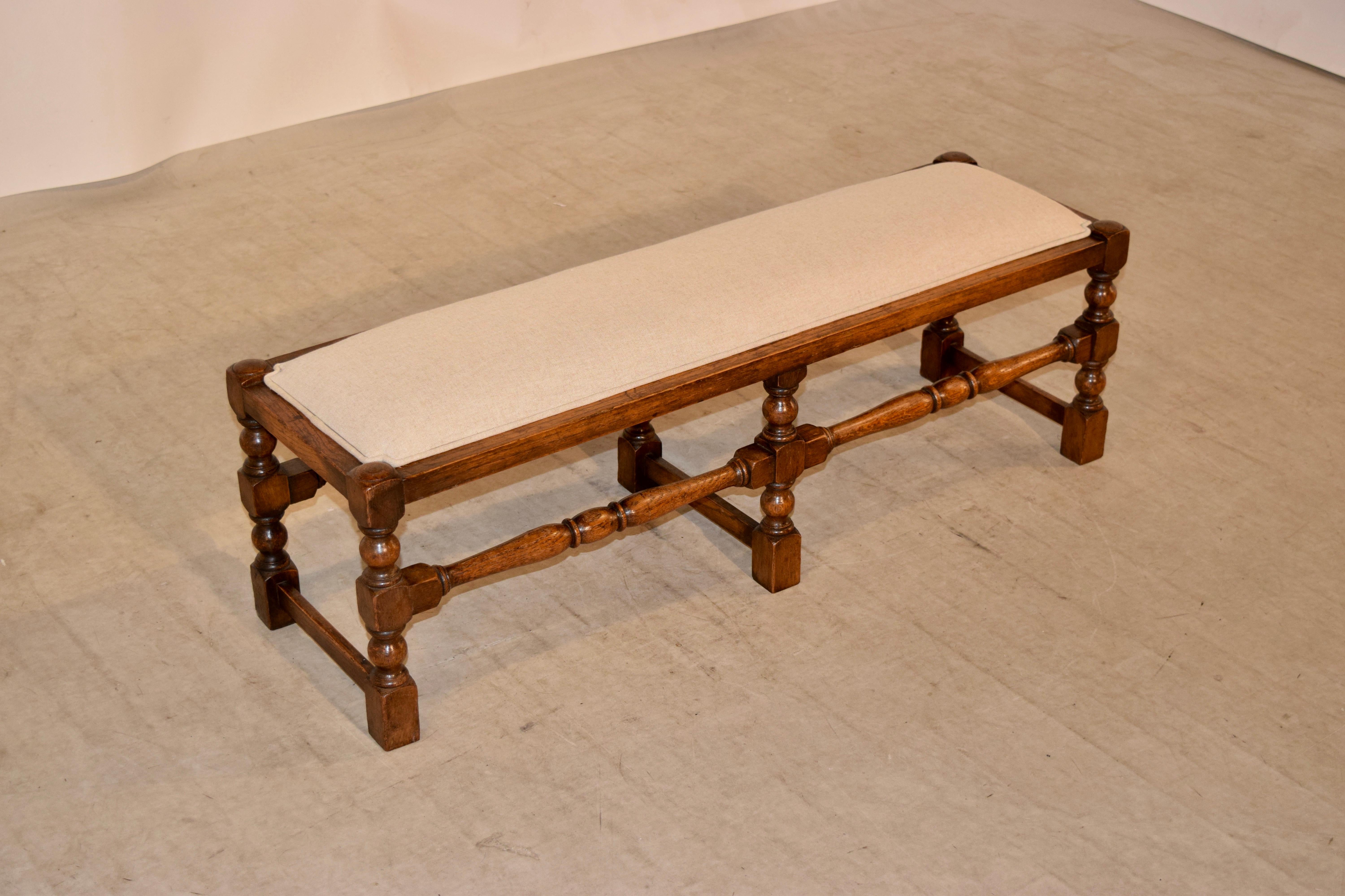 19th century English oak turned bench with a newly upholstered seat in linen, finished with a single welt decoration. The frame has hand-turned legs and stretchers.