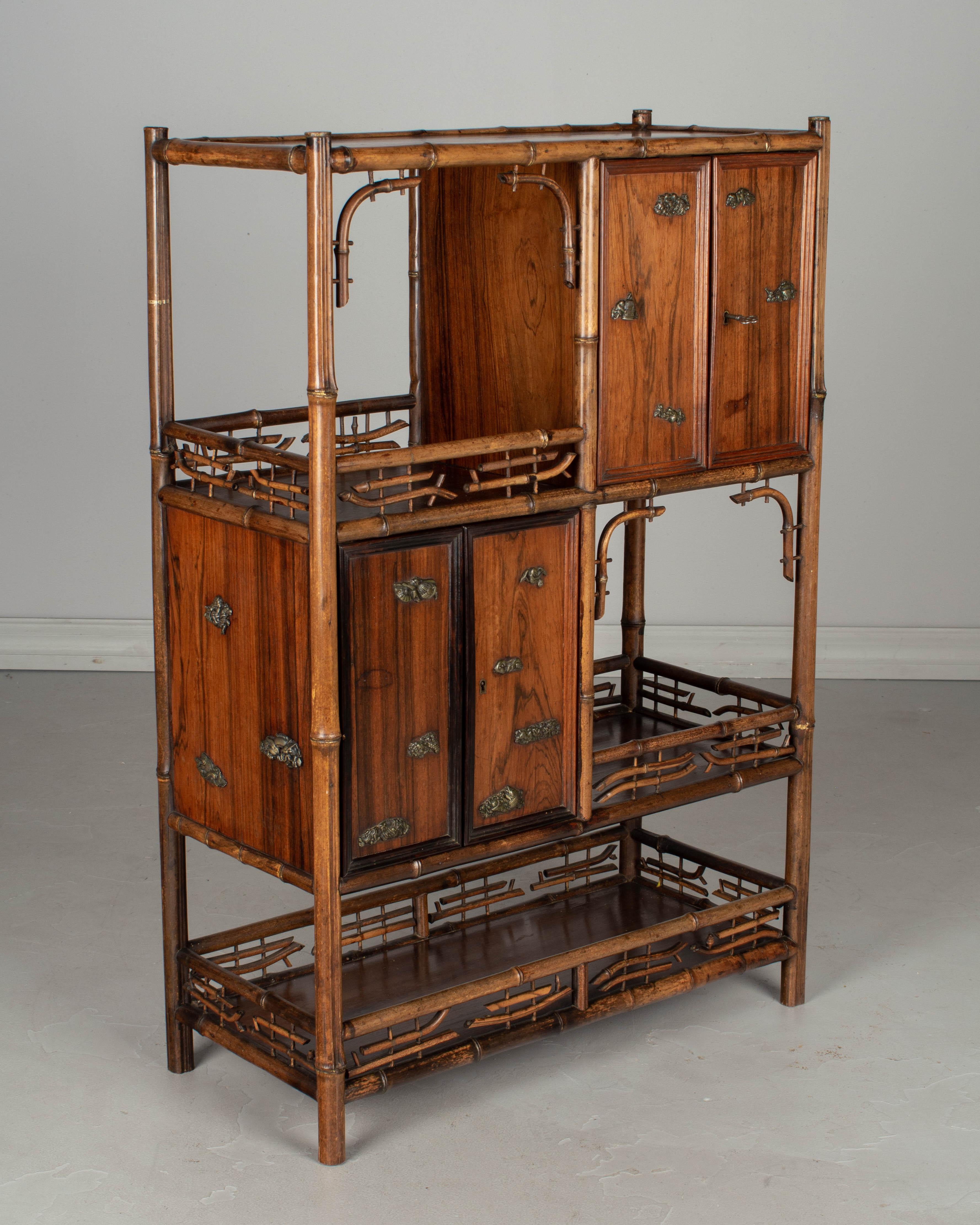 A 19th century English bamboo and rosewood Asian style étagère having open shelves with decorative bamboo galleries and two small cabinets. The cabinets are made of rosewood and have ornamental metal medallions on the doors and on the sides. Two are