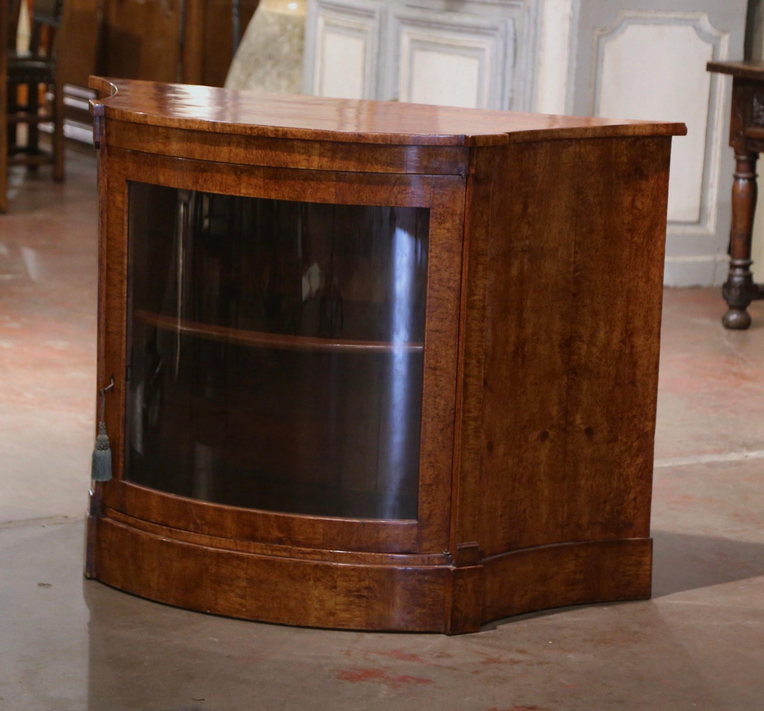 Display your fine collection in this elegant antique curio cabinet! Crafted in England circa 1870, and built of solid burl walnut wood, the vitrine sits on a flat plinth base, and features two concave side panels, a curved bow front with a