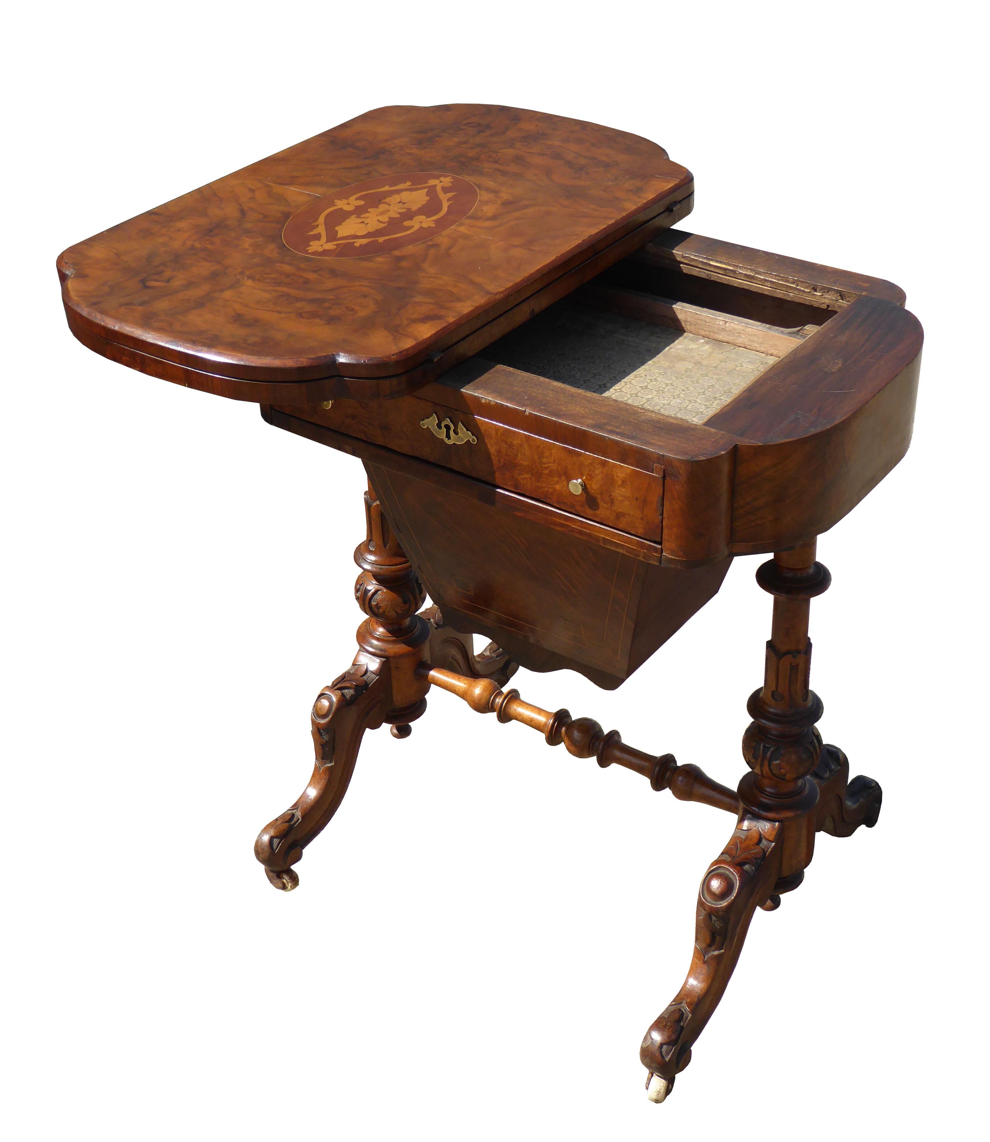 For sale is a Victorian burr walnut games table / work table, with an inlaid top swiveling and folding to reveal an interior for games. This is above a drawer, with a pullout / pull-out basket below. The table stands on ornately carved legs, joined