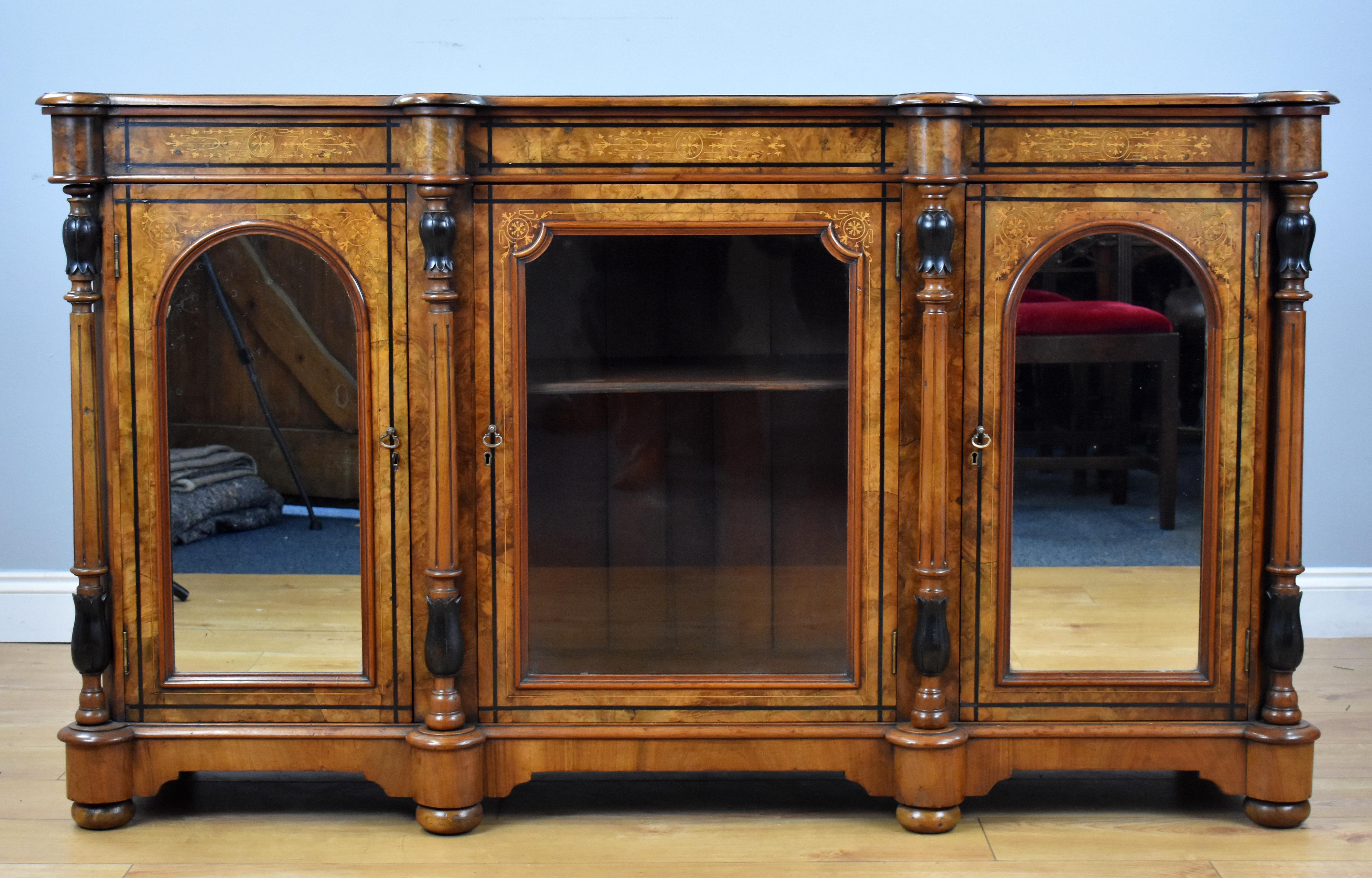 For sale is a Victorian burr walnut inlaid credenza, having a mirror door either side of a central glass door, flanked by columns. This piece is in good condition, showing minor signs of wear commensurate with age and use.

Measures: Width 62.5