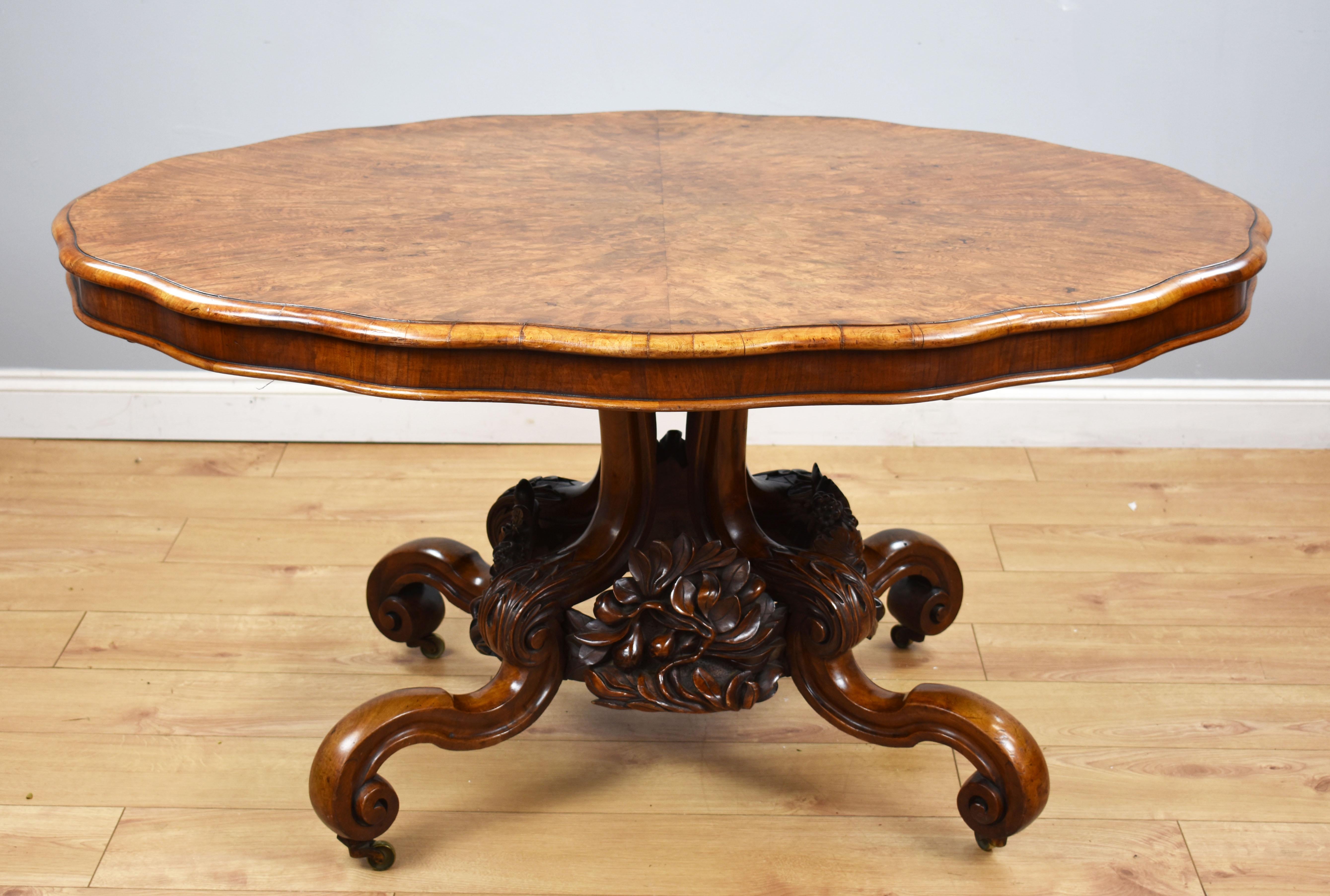 A top quality Victorian burr walnut loo table, having a well figured top, above a superbly carved base, with fruiting vine and oak leaf decoration, terminating on scroll feet raised on original castors. The table remains in very good condition,