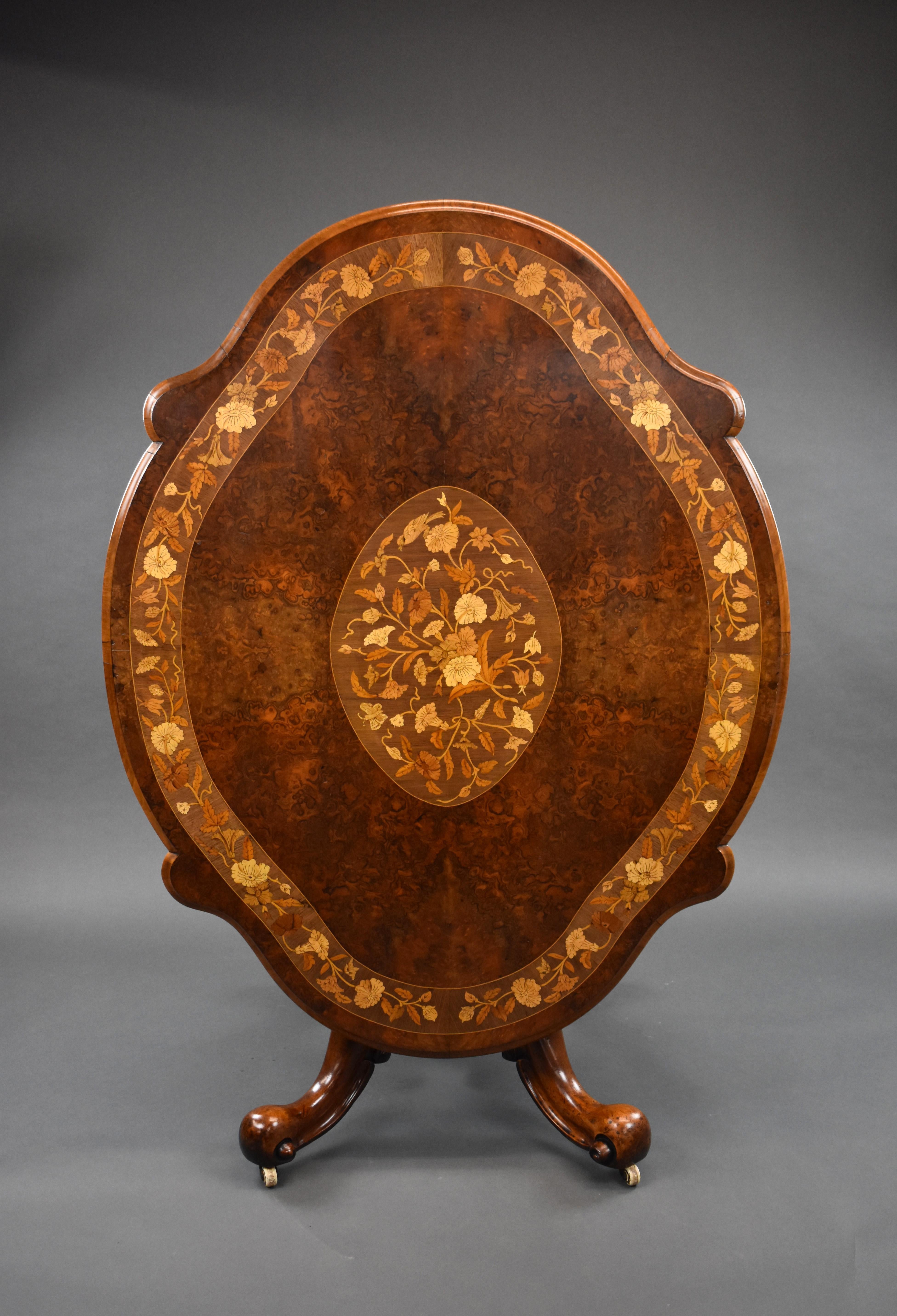 A good quality Victorian burr walnut marquetry breakfast table, the shaped top being profusely inlaid with floral marquetry around the edge, and an inlaid panel to the centre, above a turned and carved base standing on elegantly legs raised on