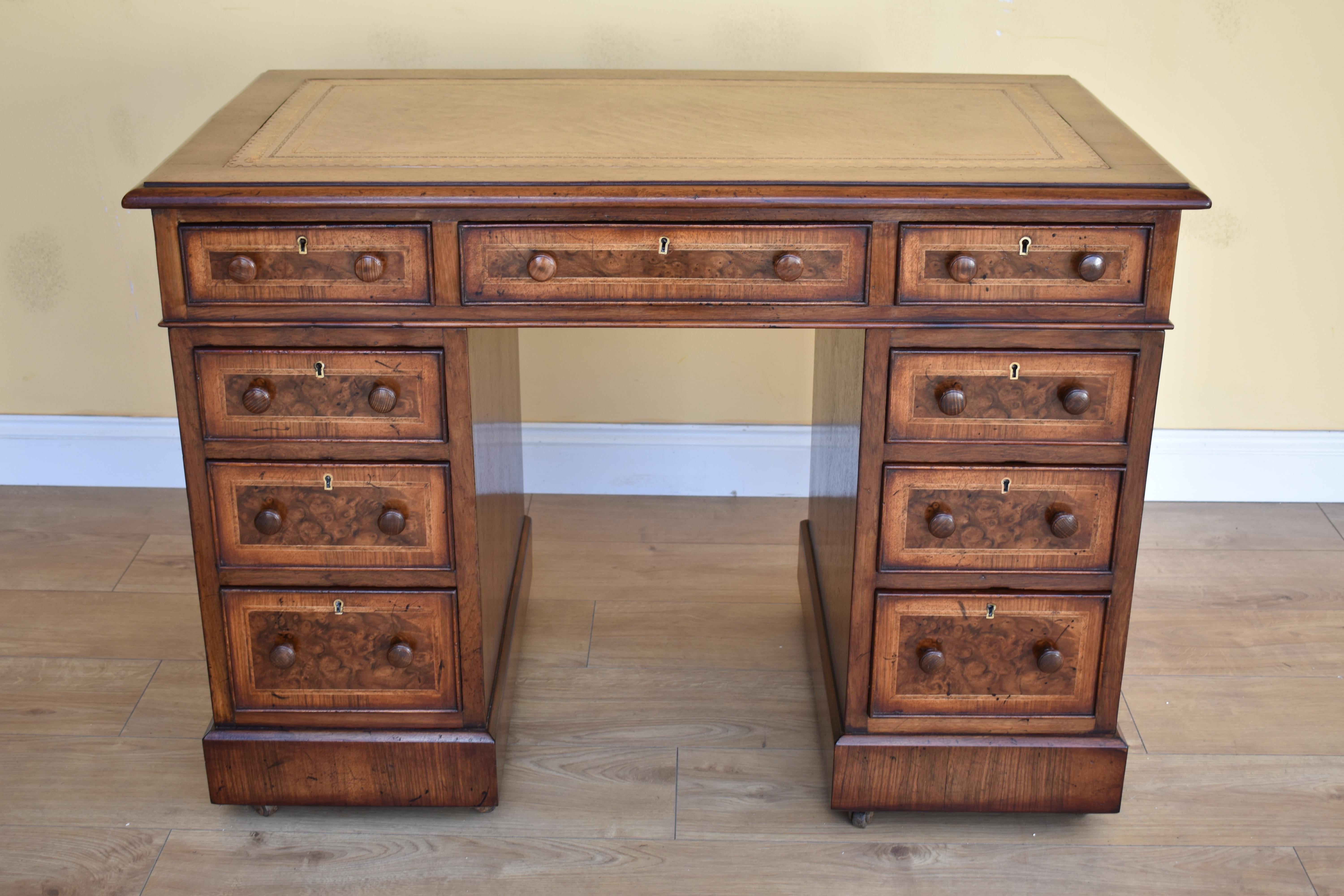 For sale is a good quality 19th century Victorian burr walnut pedestal desk. The desk top is inset with a leather skiver, decorated with gold tooling. Below this three drawers, each with walnut banding and turned handles. The top fits onto two