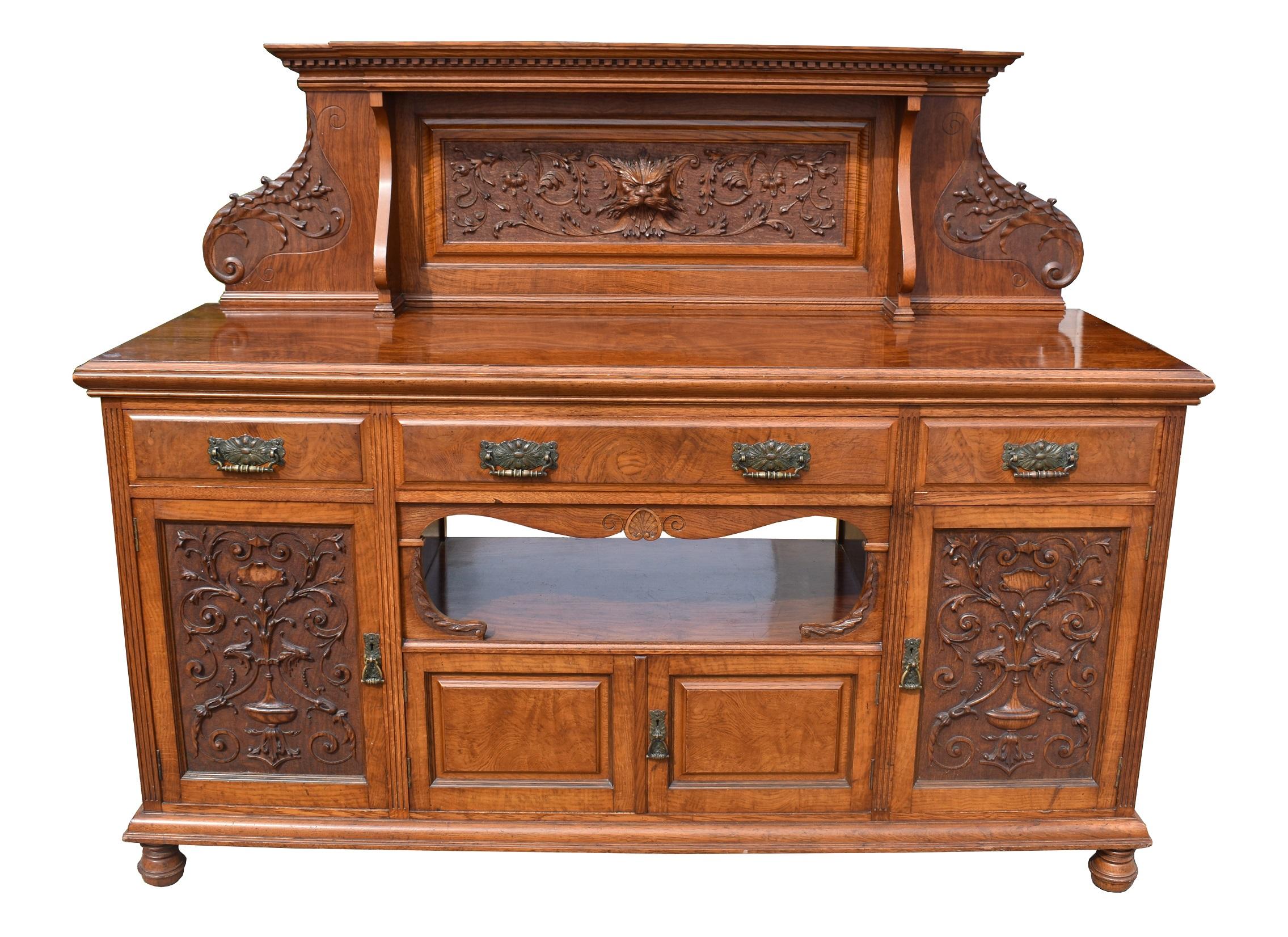 For sale is a good quality Victorian Pollard oak sideboard, the top with a carved pediment, above three drawers, each with brass handles. The base has two large cupboards with carved panels, as well as a shelf with a small cupboard below. The