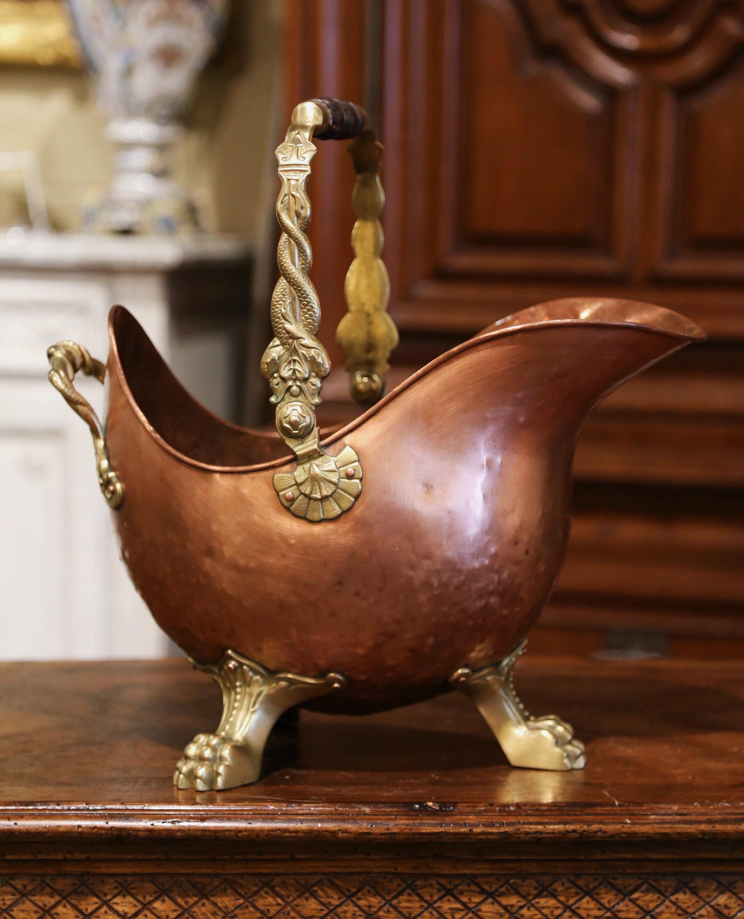 This antique coal scuttle was created in England, circa 1880. Built of copper with an intricate brass and turned walnut handle, the oblong bucket stands on three paw feet. The decorative box is in excellent condition with a rich patinated copper