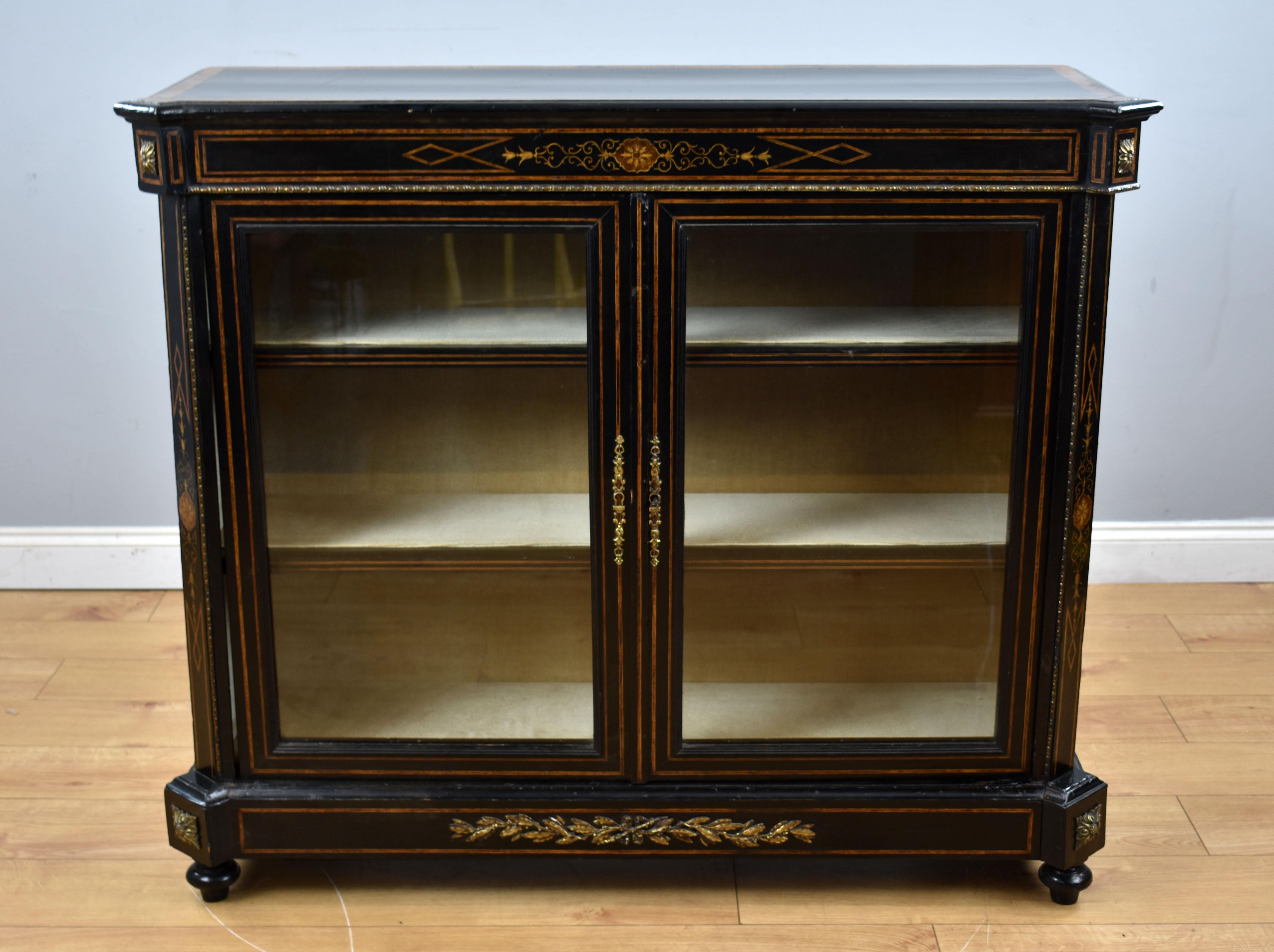 For sale is a Victorian ebonised pier cabinet, having a walnut banded top, above two glazed doors opening to a fabric lined the interior, the cabinet is inlaid throughout and stands on small turned feet. The cabinet is in good condition, showing