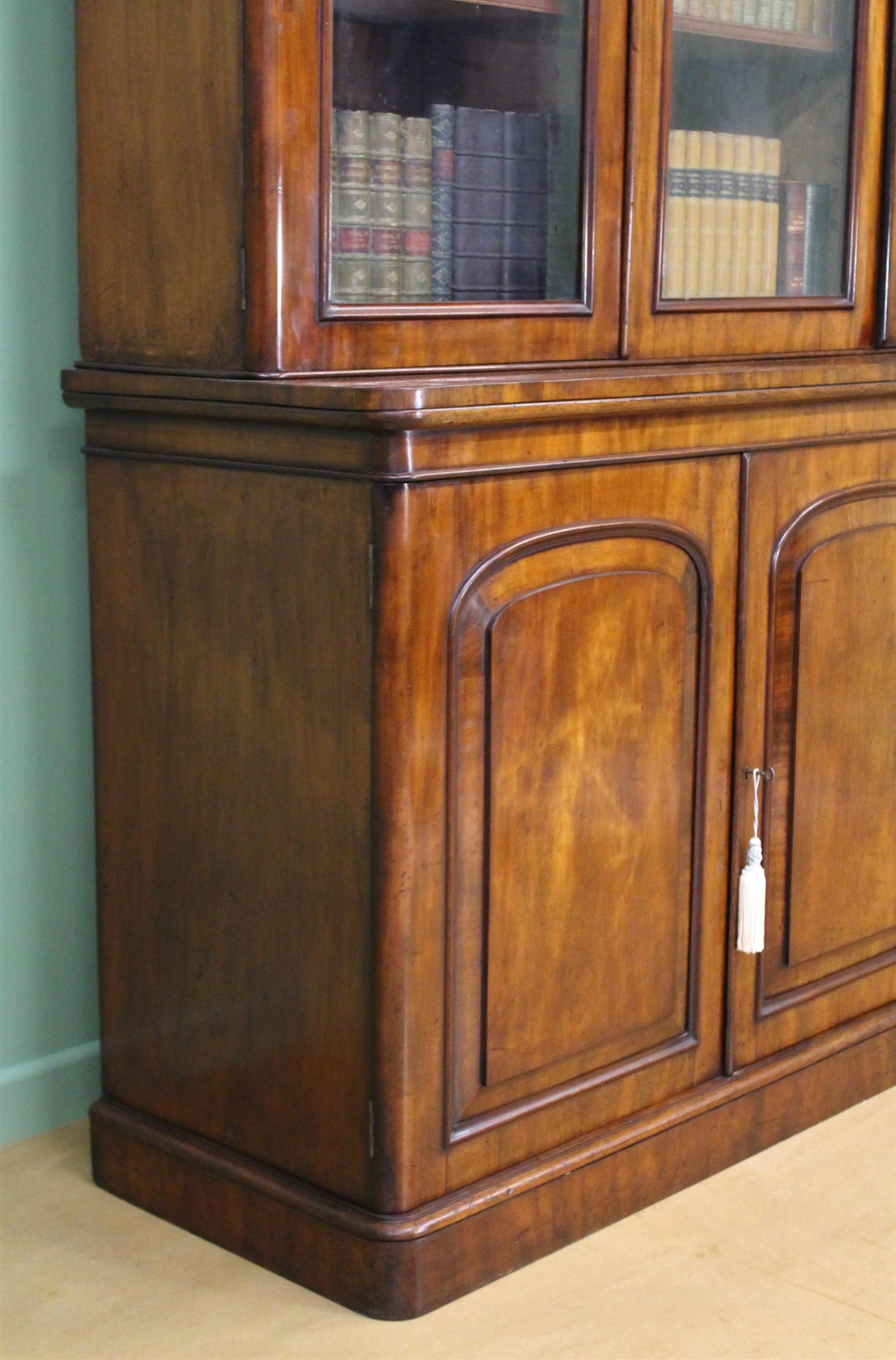 A splendid Victorian period figured mahogany library bookcase. Of fine construction in solid mahogany with attractive figured mahogany veneers. With 3 glazed doors over 3 cupboard doors. All doors open to access shelved interiors, affording a wealth