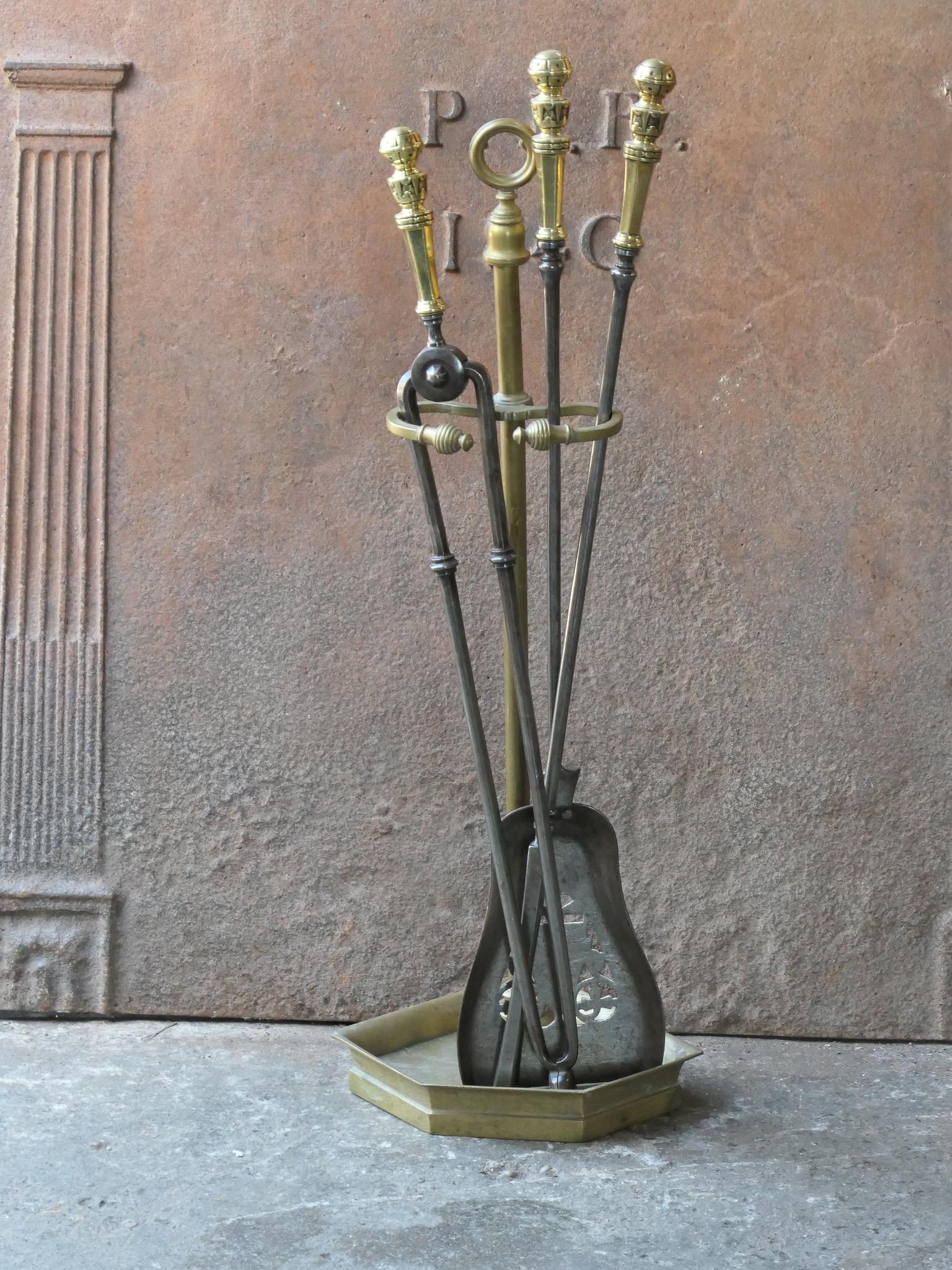 Ensemble d'outils pour cheminée du 19e siècle, d'époque victorienne anglaise. Les outils sont en fer forgé avec des poignées en laiton, tandis que le support est en laiton. L'ensemble d'outils comprend une pince, un tisonnier, une pelle et un