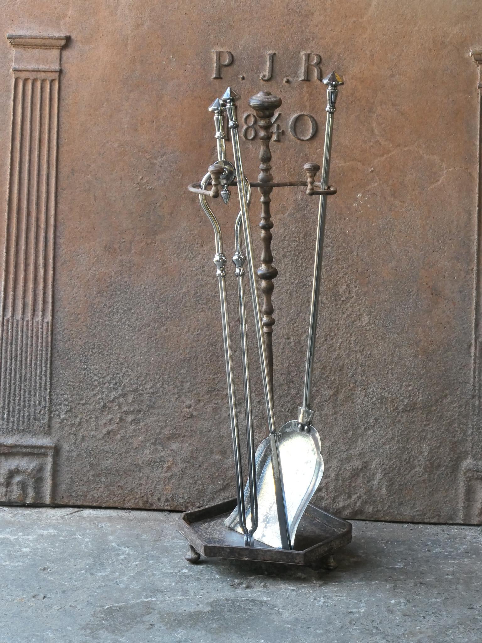 Ensemble d'outils pour cheminée du 19e siècle, d'époque victorienne anglaise. Les outils sont en acier poli, tandis que le support est en fer forgé et en fonte. L'ensemble d'outils comprend une pince, un tisonnier, une pelle et un support. L'état