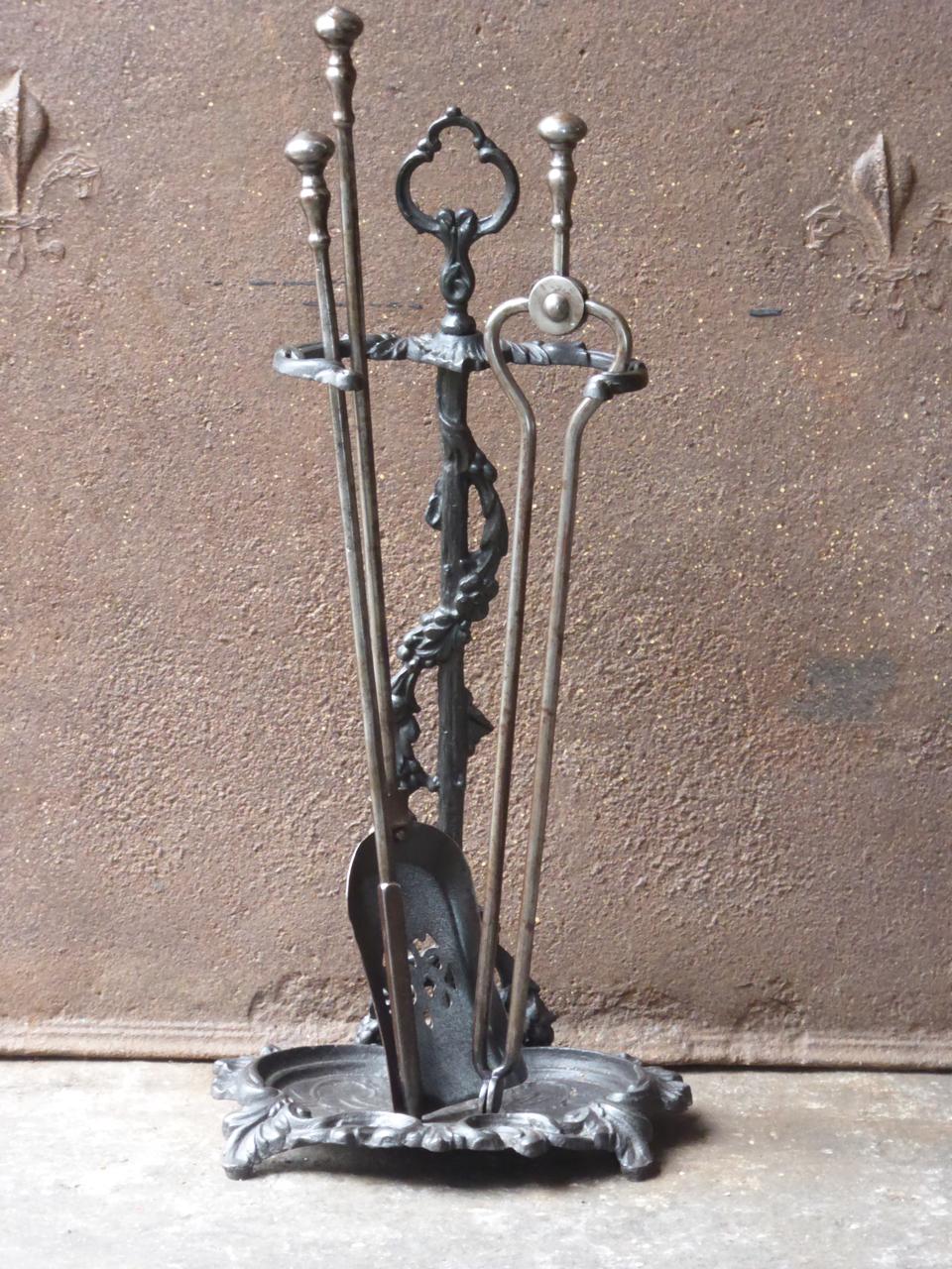 19th century English Victorian fireplace toolset made of cast iron and wrought iron. The toolset consists of three tools and a stand.

We have a unique and specialized collection of antique and used fireplace accessories consisting of more than 1000