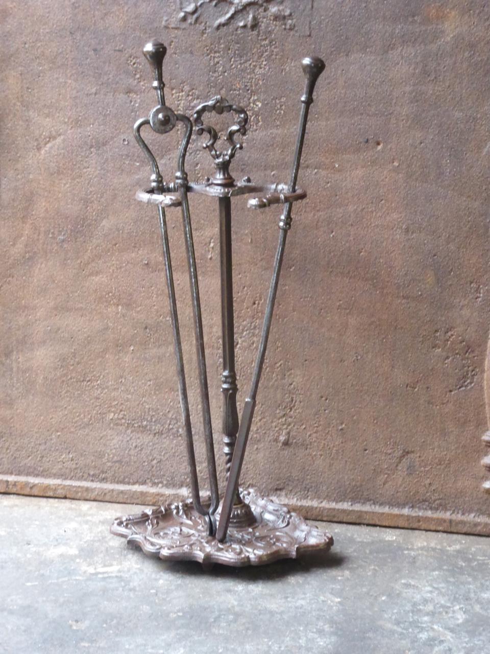 19th century English Victorian fireplace toolset. The toolset is made of cast iron and wrought iron. It consists of a stand with two fireplace tools. The toolset is in a good condition and is fully functional.

