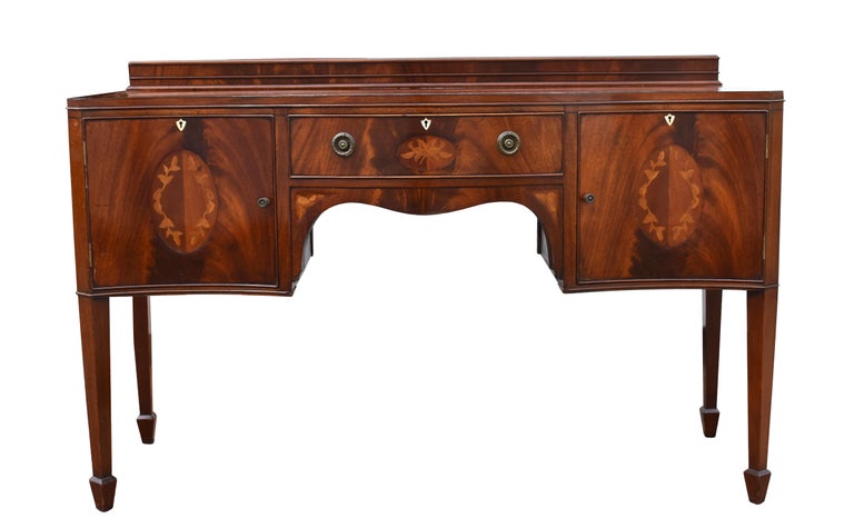 For sale is a good quality 19th century flame mahogany and inlaid serpentine sideboard, having a floral inlaid border to the top, above a single drawer to the centre flanked by cupboards on either side. The sideboard stands on elegant tapering legs