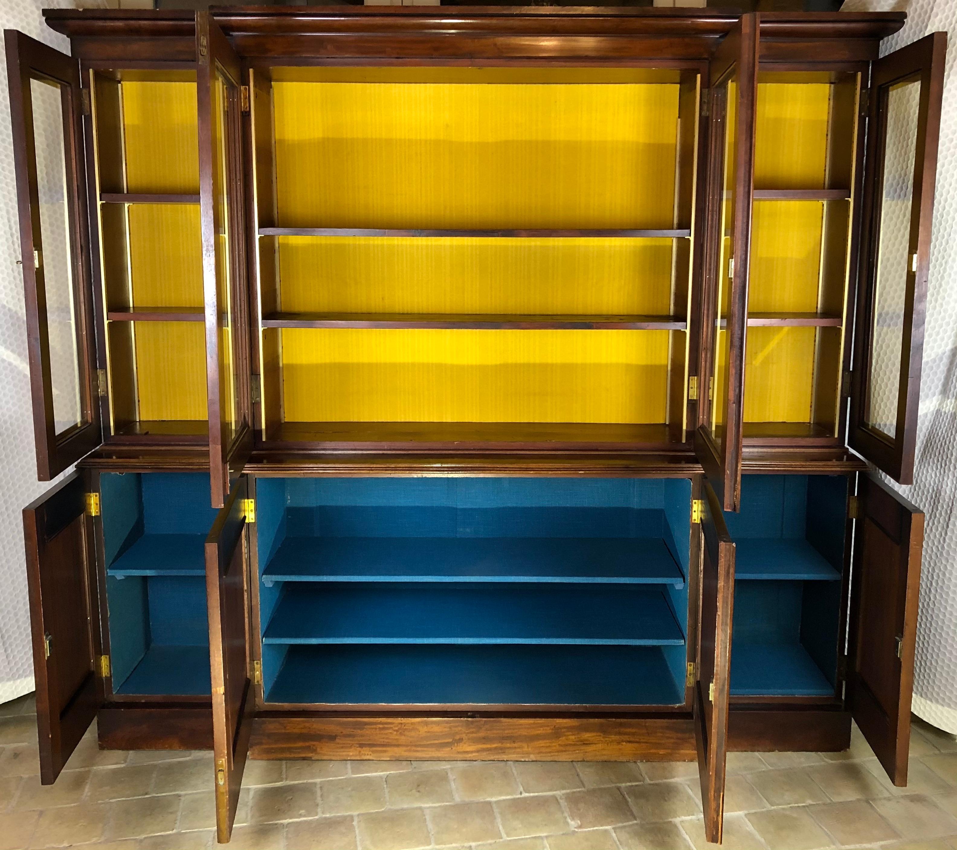 A beautiful antique early 19th century Victorian bookcase, masterfully crafted in rich solid mahogany, circa 1850.

This bookcase features four paneled doors in the upper and lower sections, all of which open to reveal spacious cupboards each with