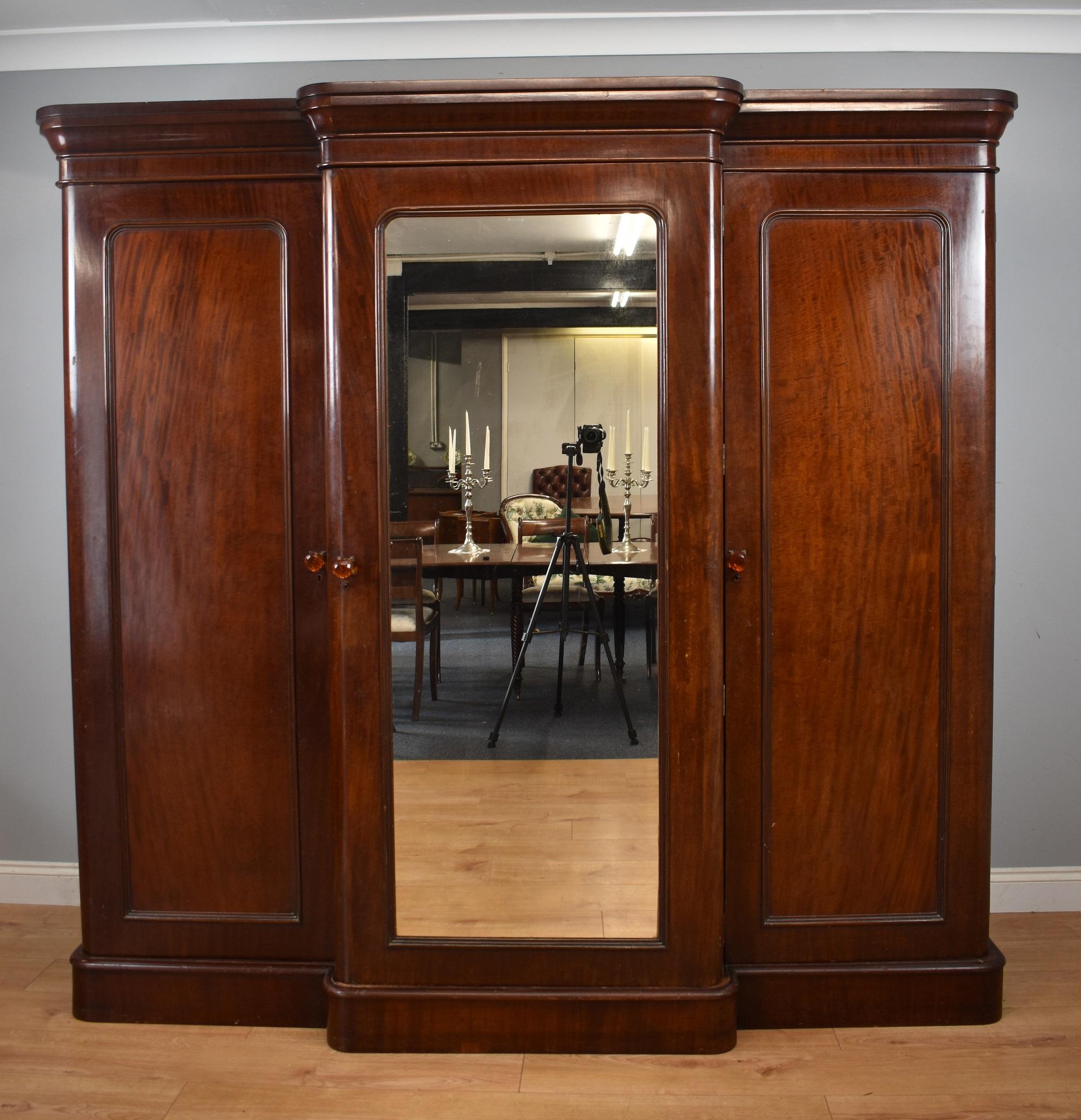 For sale is a good quality 19th century Victorian Mahogany Breakfront Triple Wardrobe, have a stepped and flared cornice, above three doors, the centre of which having a mirror, opening to reveal a fitted interior consisting of linen trays to the