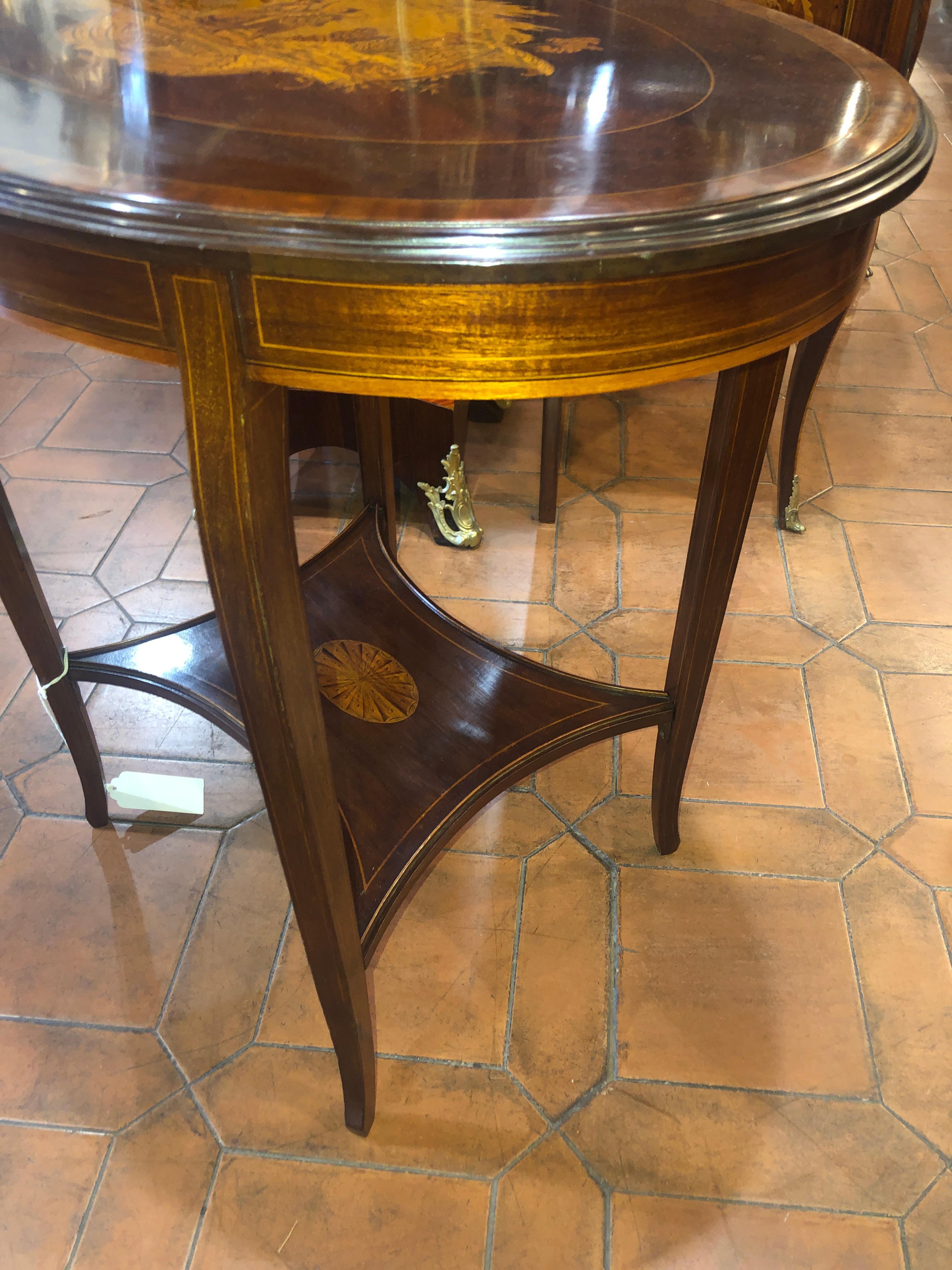 English oval table, finely inlaid with characters, of excellent workmanship. End of the Victorian period, circa 1890. In mahogany wood and inlays in fruitwood, details finished in ink.