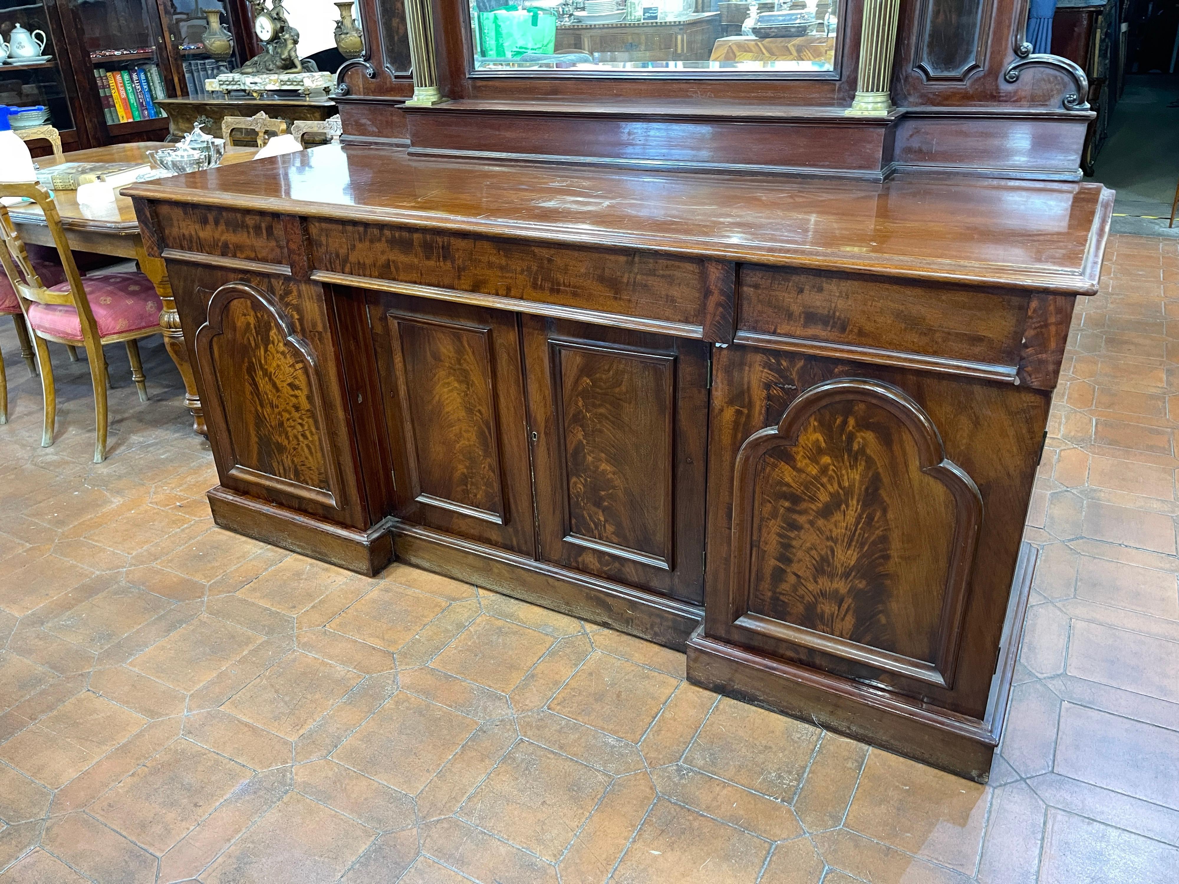 Beautiful English sideboard mirror back, late Victorian era (1880 circa), in mahogany wood and brass applications on the columns of the mirror.
Sideboard with four doors and three drawers, with mahogany and mahogany feather, embellished with two