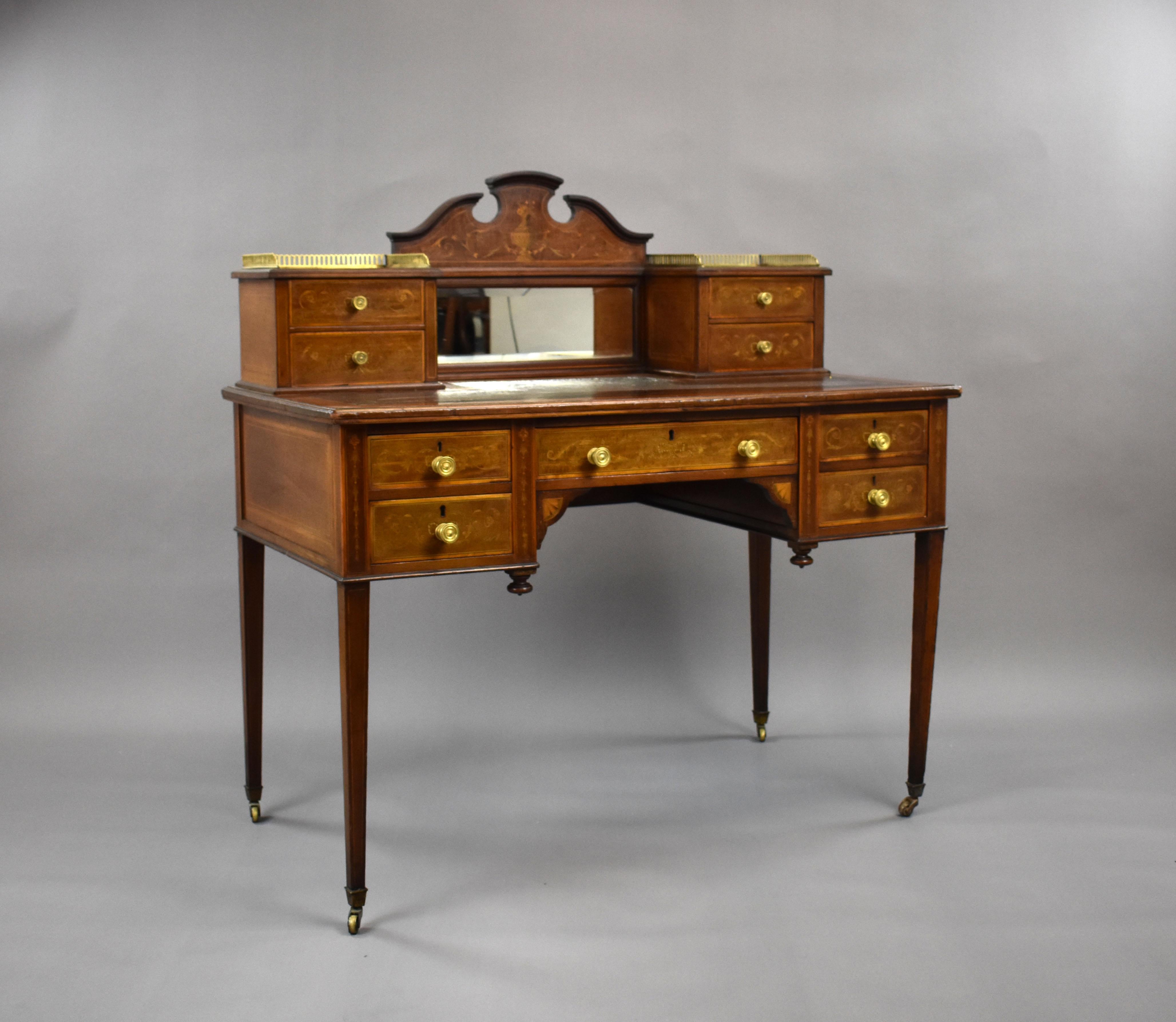 For sale is a good quality Victorian Mahogany, Satinwood Banded and Marquetry Inlaid Writing Desk by James Shoolbred & Co, the moulded pediment above a bevelled glass mirror plate flanked by four small drawers and a pierced brass gallery, the red