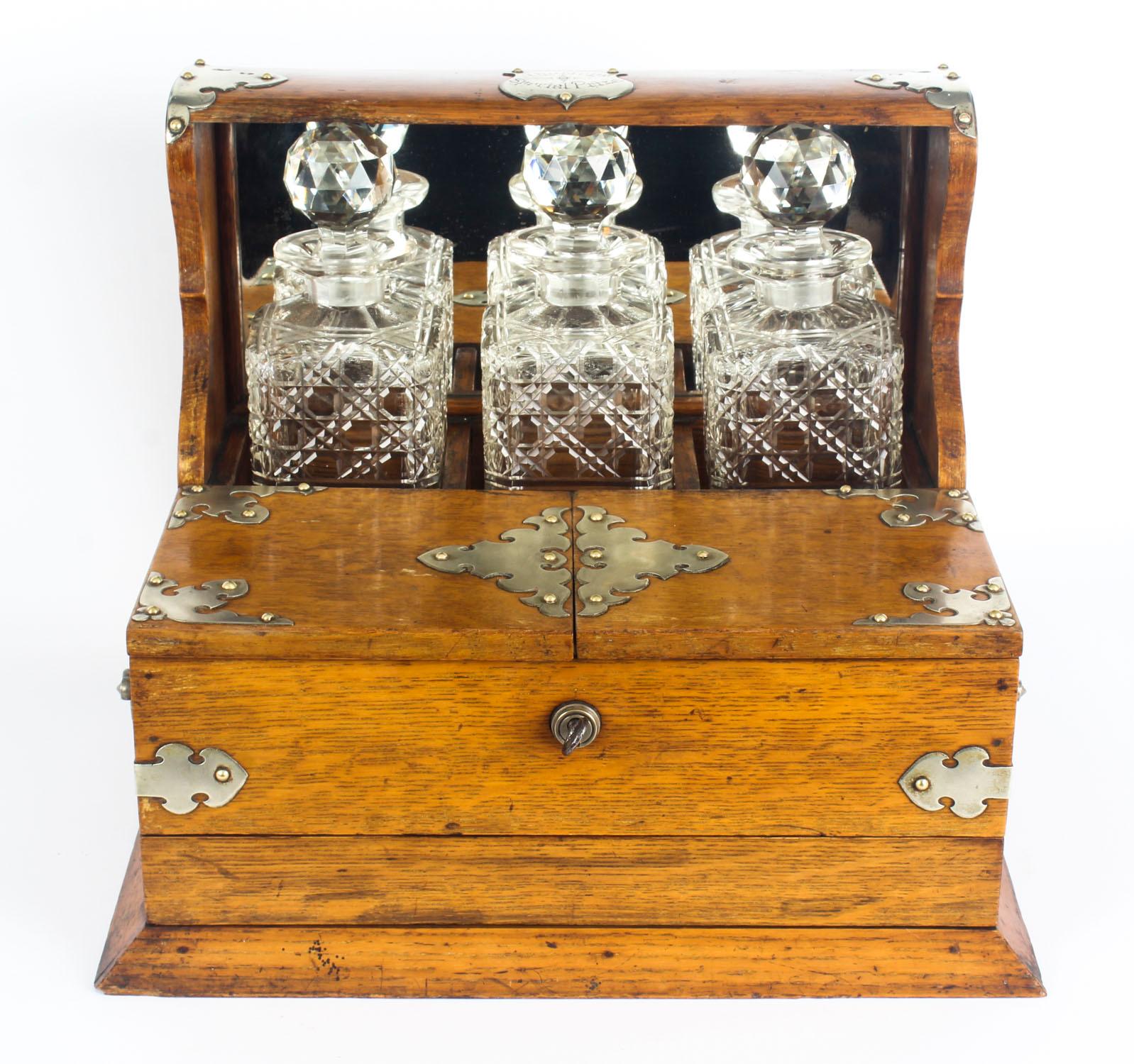 This is a superb antique Victorian oak cased three decanter tantalus with decorative silver plated cut brass mounts, shield marked 