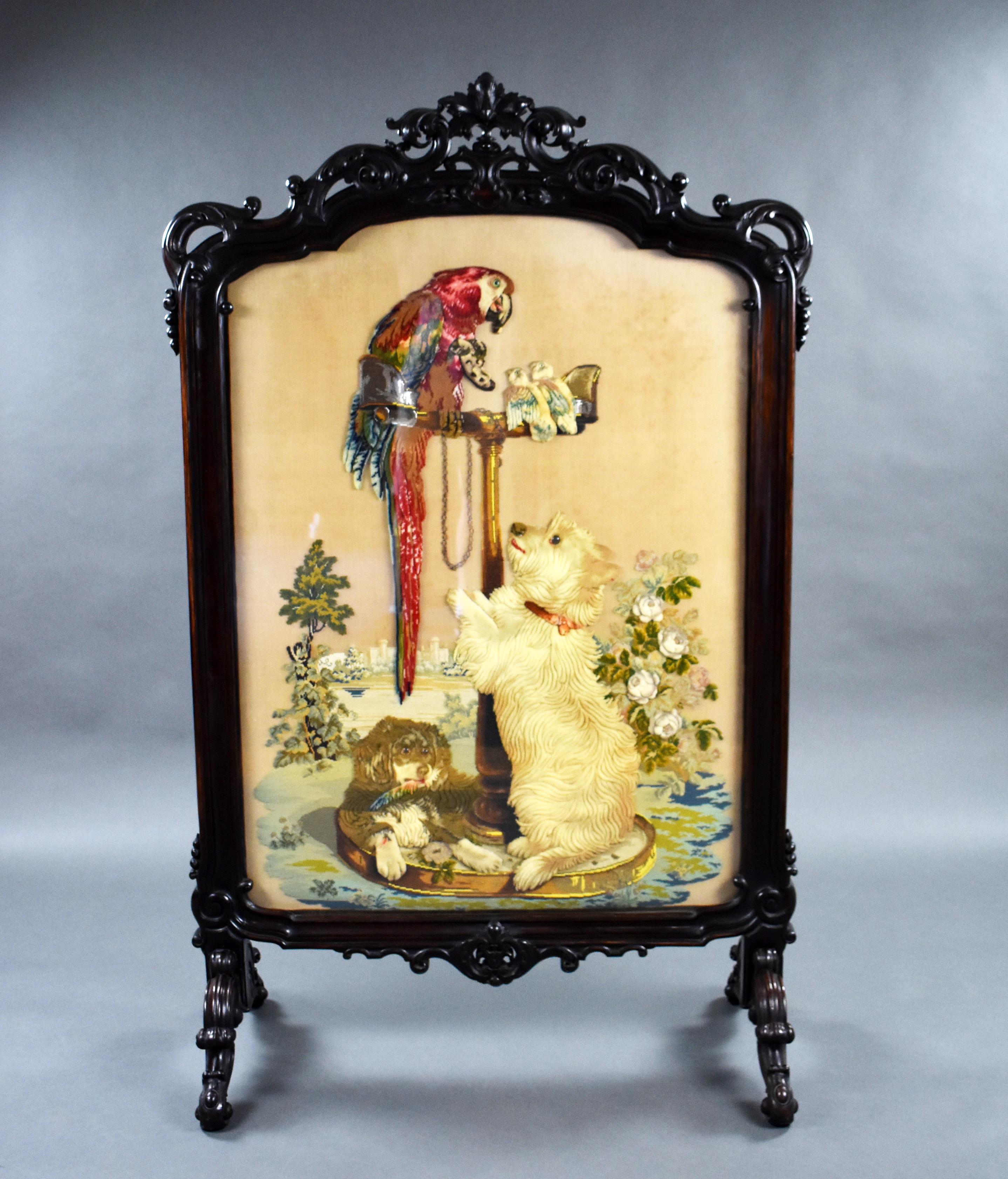 For sale is a fine and rare large Victorian rosewood screen, having an ornately carved top, above embroidery, depicting a dog jumping up at a parrot on a perch, with two other small birds on the perch beside it another dog lies on the base of the