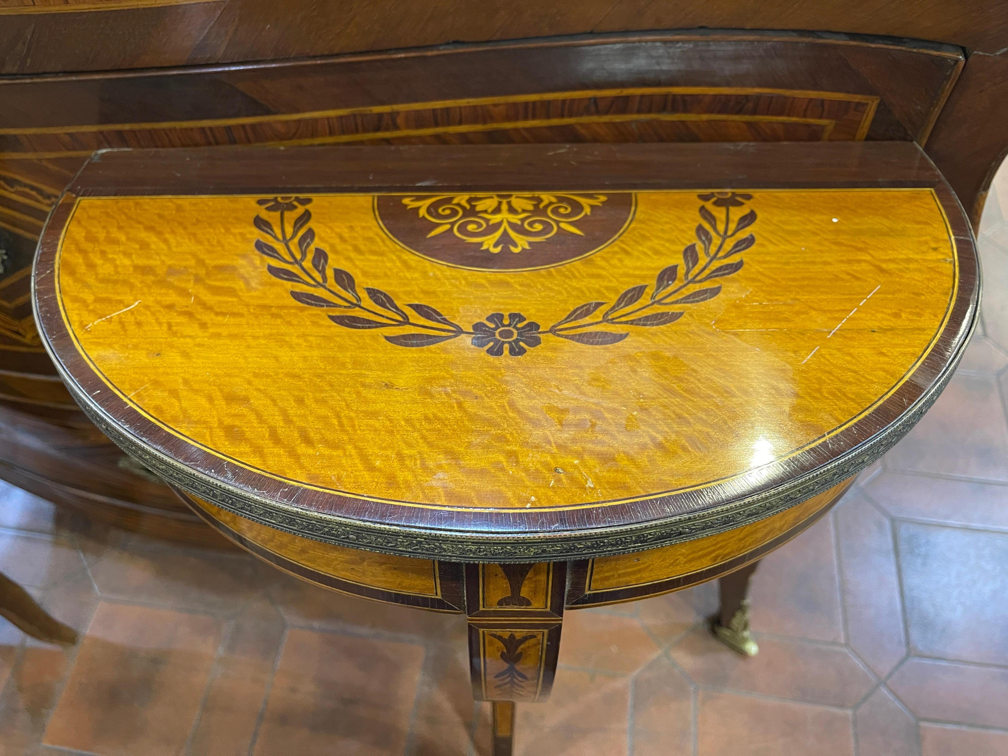 Fantastic wall console, in Satinwood and with use of walnut and boxwood for inlays and trim on the edges, around the top a worked bronze that embellishes the flat front. Floral inlays on the top, leg and top edge. In excellent state of preservation.