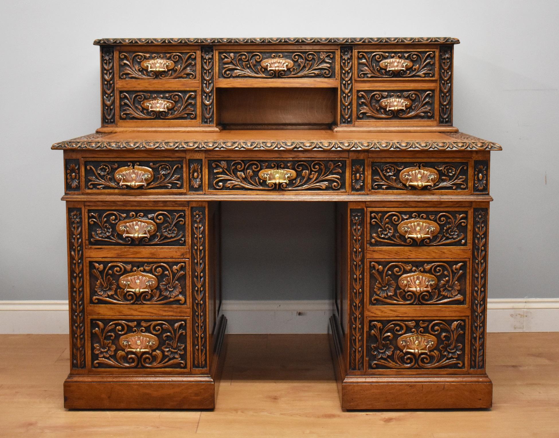 For sale is a good quality Victorian solid oak carved pedestal desk. The top of the desk has an arrangement of five drawers, each profusely carved and has very decorative copper handles. Below this is a brown leather insert with decorative tooling.