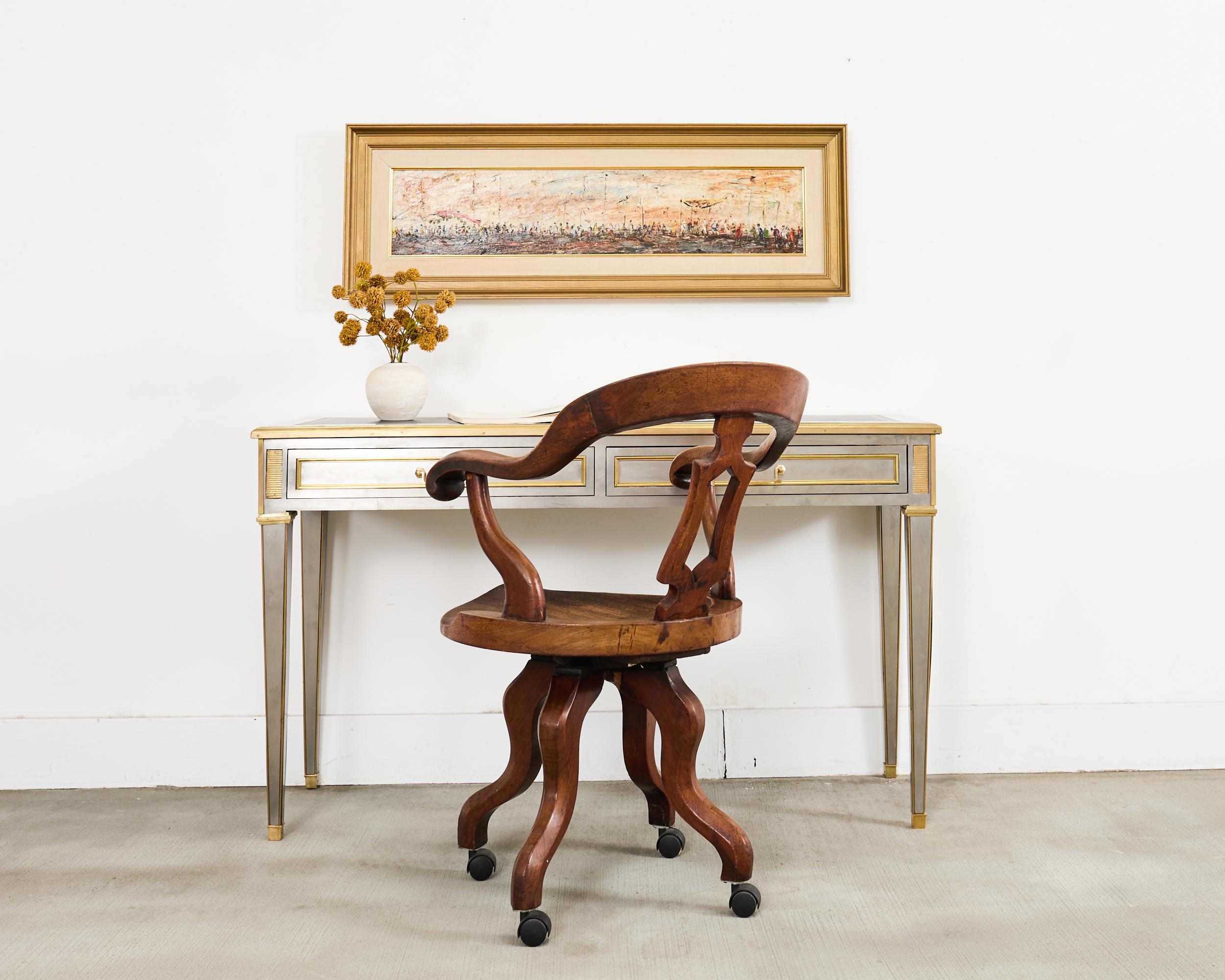 Handsome 19th century English Victorian period captains chair or smokers' bow chair crafted from mahogany. The chair features a round horseshoe shaped seat crest with a deep contoured saddle seat. The generous seat has a swivel mechanism and a