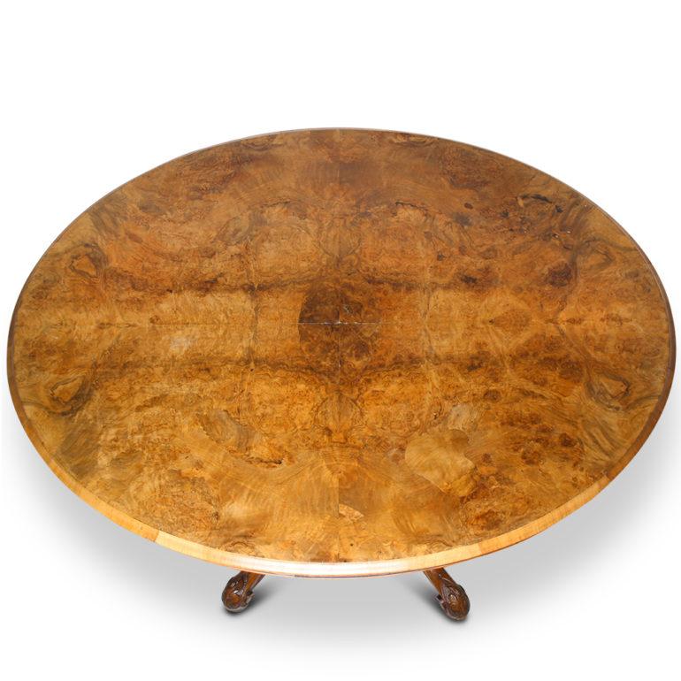 English Victorian oval tilt-top ‘loo’ table, the walnut pedestal base with four carved legs, the top with quarter book-matched highly- figured burl walnut veneer.



