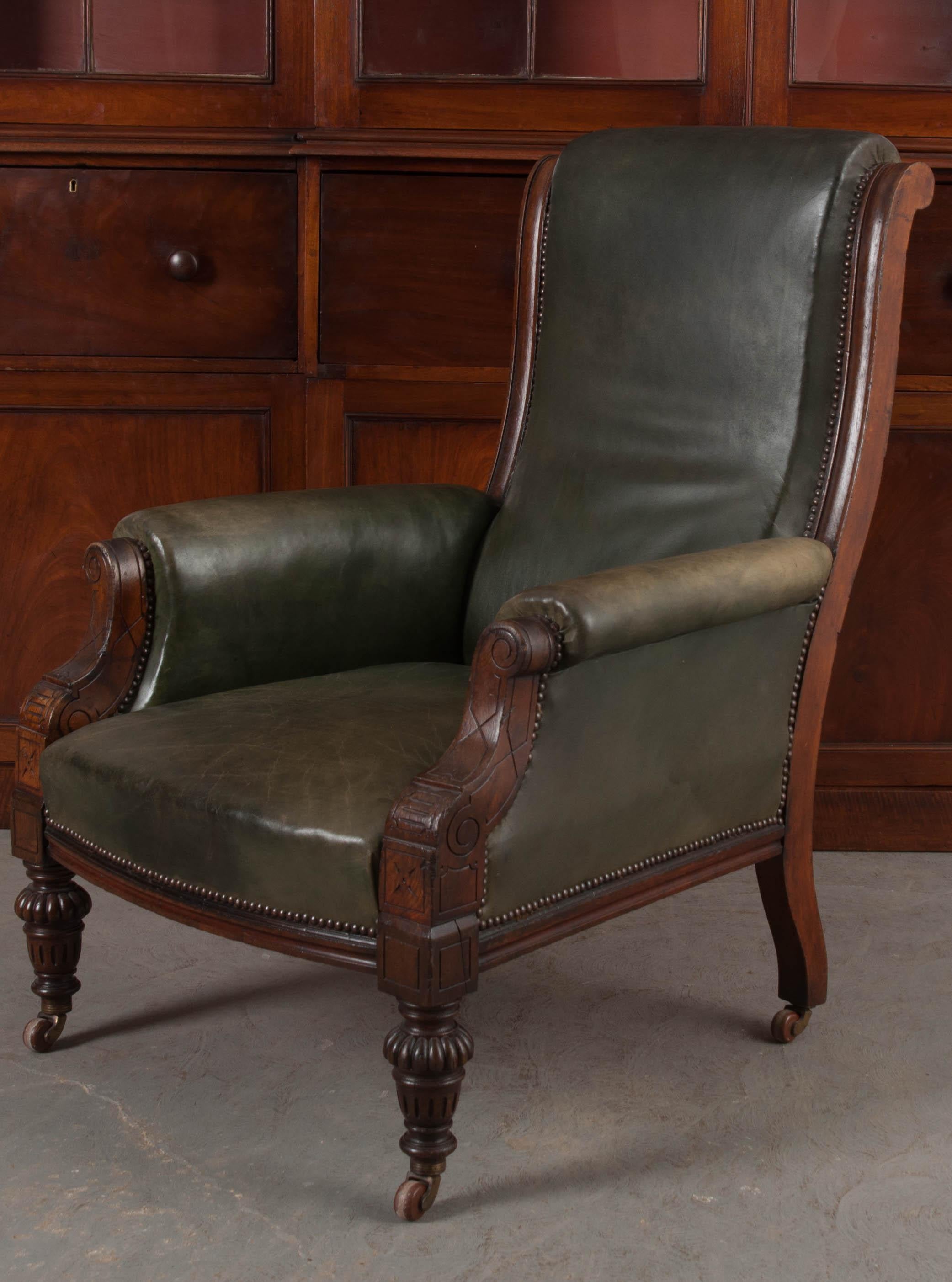 A stunning solid-walnut Georgian style armchair from 19th century England. Upholstered in an exquisite patinated green leather, the armchair looks like it would be owned by an informed individual. One that spends hours each day reading and