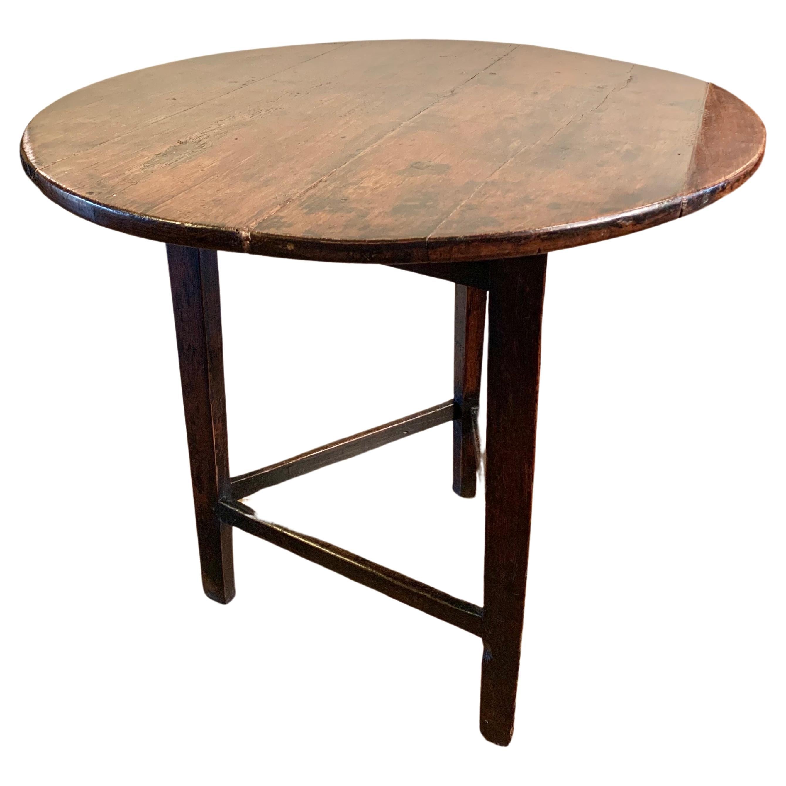 This English Cricket Table was crafted in the late 1800's from old growth walnut. The piece features a circular top resting on three legs that have been adjoined with triangular stretchers. Cricket tables are in essence English pieces of furniture